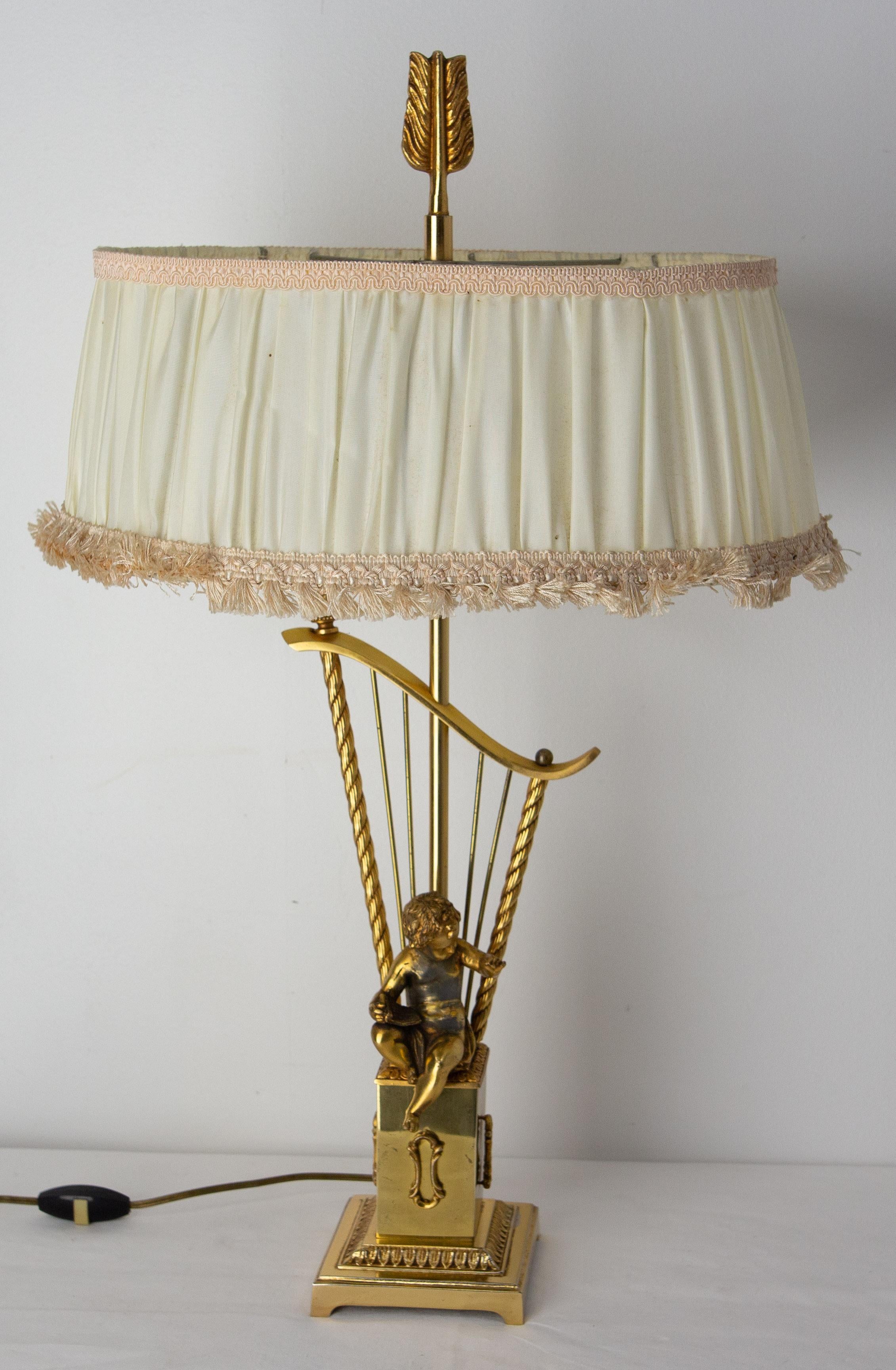 Brass table lamp.
Elegant lamp for a dining room, a living room or an entrance, perfect to create a subdued atmosphere.
A reading angel is depicted at the foot of the lamp, seated on a pedestal. 
The top of the lamp represents the stem of an