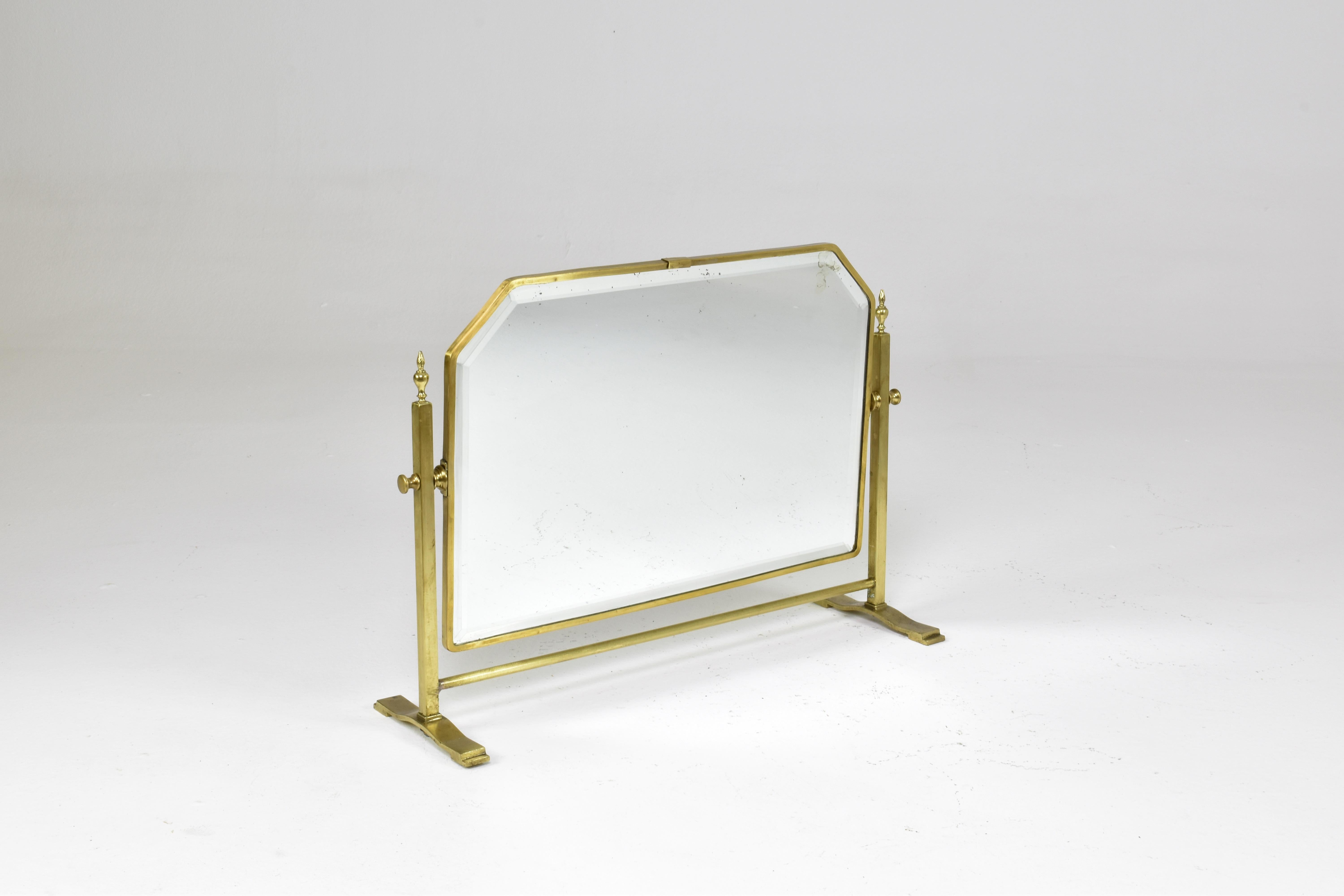 A fantastic French circa 1930s table mirror framed in solid brass, featuring an adjustable tilting mechanism. Its refined design includes decorative finials making it a timeless addition to any dressing table, console, or vanity setup.
The mirror's