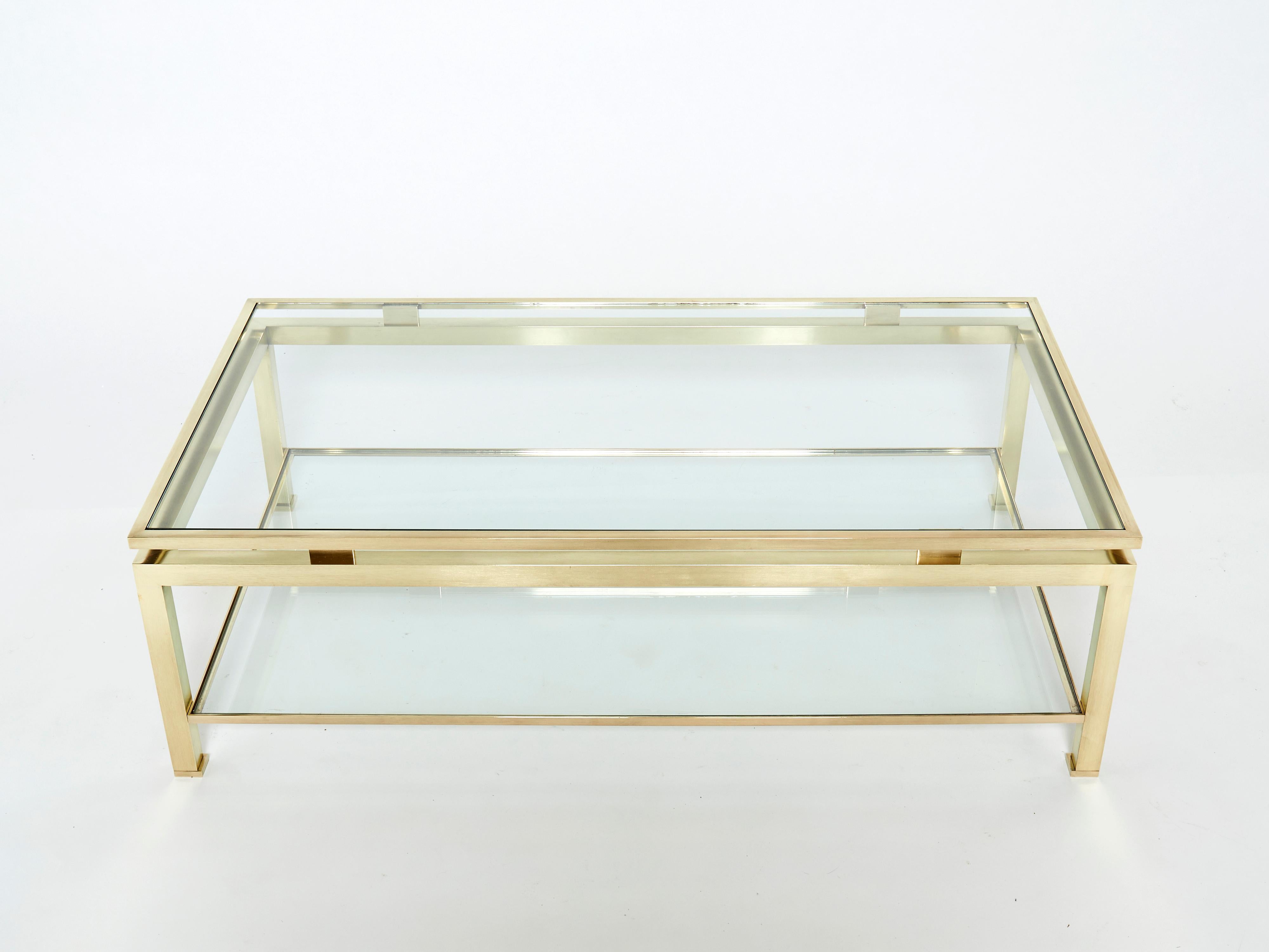 Simple lines point to this two-tier coffee table's french mid-century roots. Designed by Guy Lefevre for Maison Jansen, it features silky brass legs and transparent glass tops. Its symmetry, elevated glass, asian inspiration and strong architectural