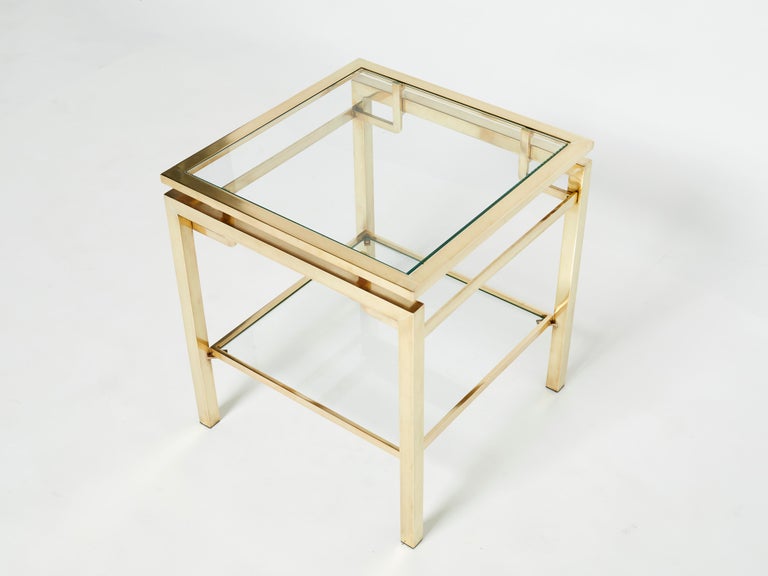 Simple lines point to this two-tier end table French mid-century roots. Designed by Guy Lefevre for Maison Jansen, it features silky brass legs and transparent glass tops. Its symmetry, elevated glass, Asian inspiration and strong architectural