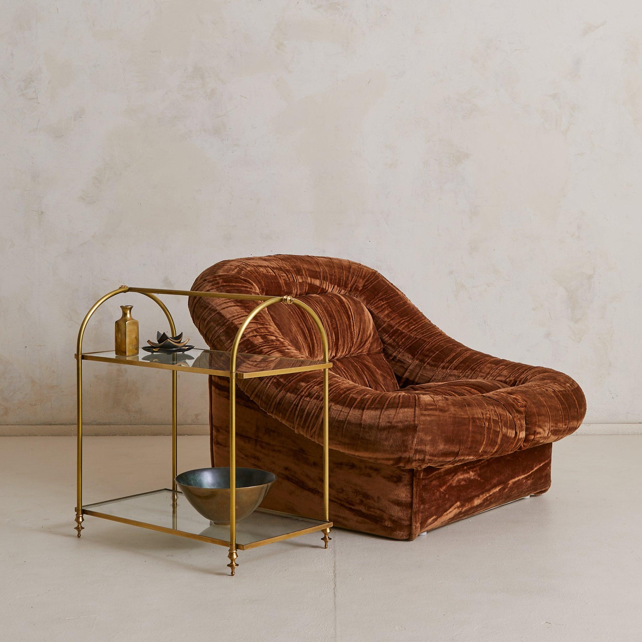 Elegant in proportion, this 1940s French two-tier side table channels the neoclassical language of Maison Jansen. Crafted in solid brass with a soft, time-worn patina, its arched supports and finial feet strike a poised silhouette. Two glass