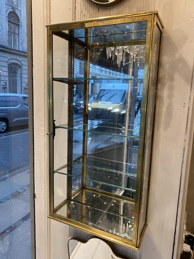 Handsome French wall vitrine, made of quality brass and original glass (including three height adjustable matching shelves). It comes with its original key.

This lovely display cabinet was part of a boutiques inventory, and is in very good