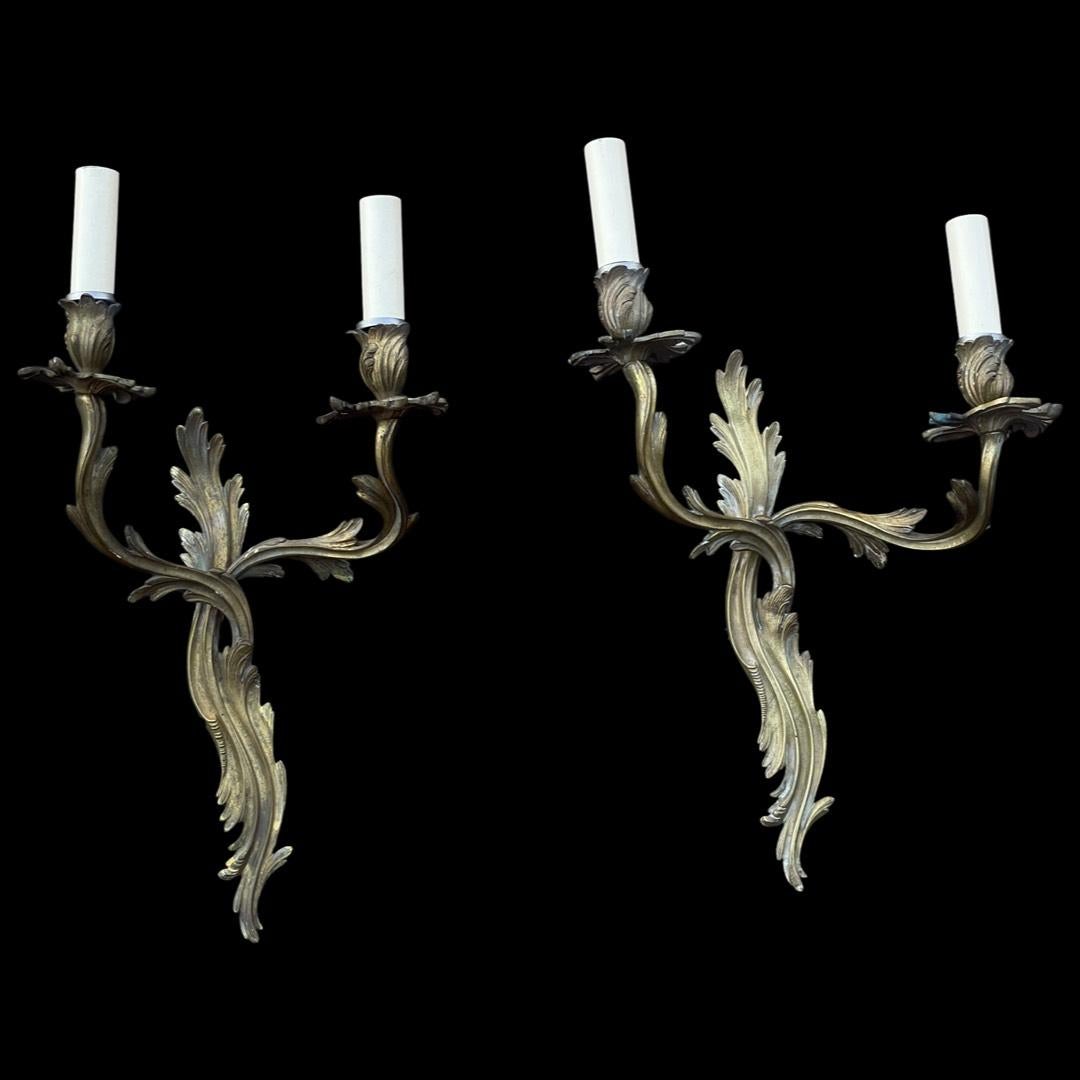 Presenting an exquisite pair of French brass wall lights adorned with a captivating patina, embodying timeless elegance.

Crafted to emulate the grace of vine leaves, their intricately curved intertwined arms showcase unparalleled artistry.