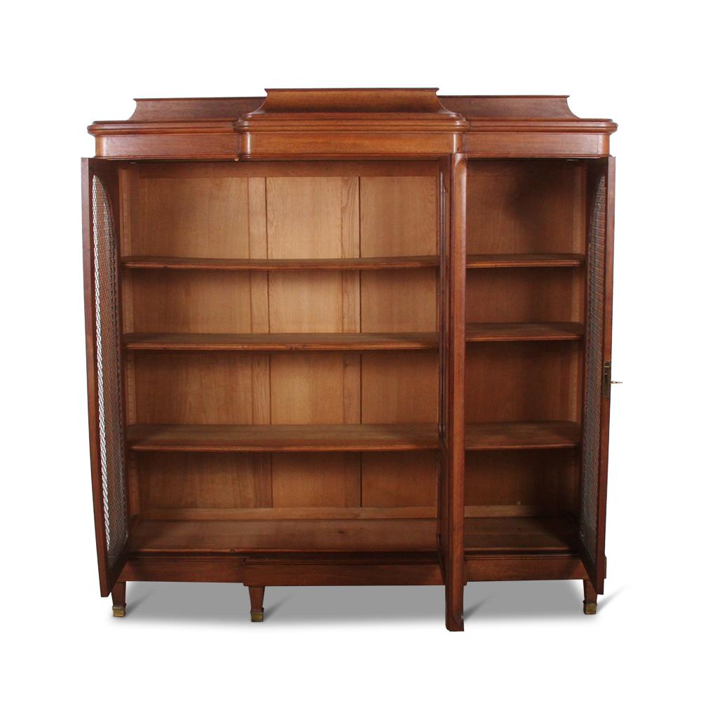 A French breakfront bookcase in walnut with floral Art Nouveau influence to the shaped curved doors and carved details. Features gilt mesh and adjustable shelving.


   