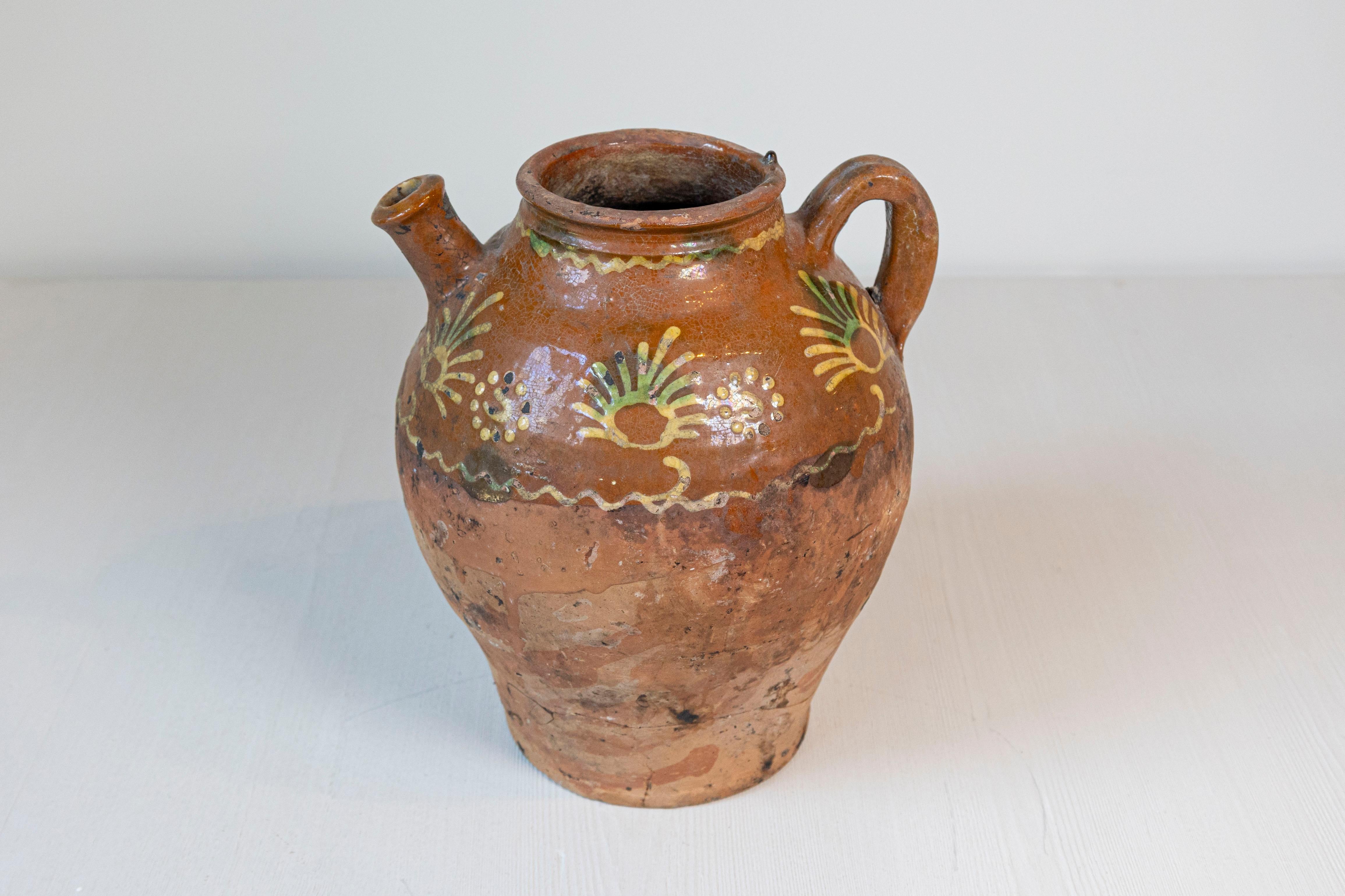 French Bressane pottery jug from the 19th century with brown glaze and soft yellow motifs. A charming French Bressane pottery jug from the 19th century, enveloped in a brown glaze adorned with soft yellow motifs, melding rustic character with an