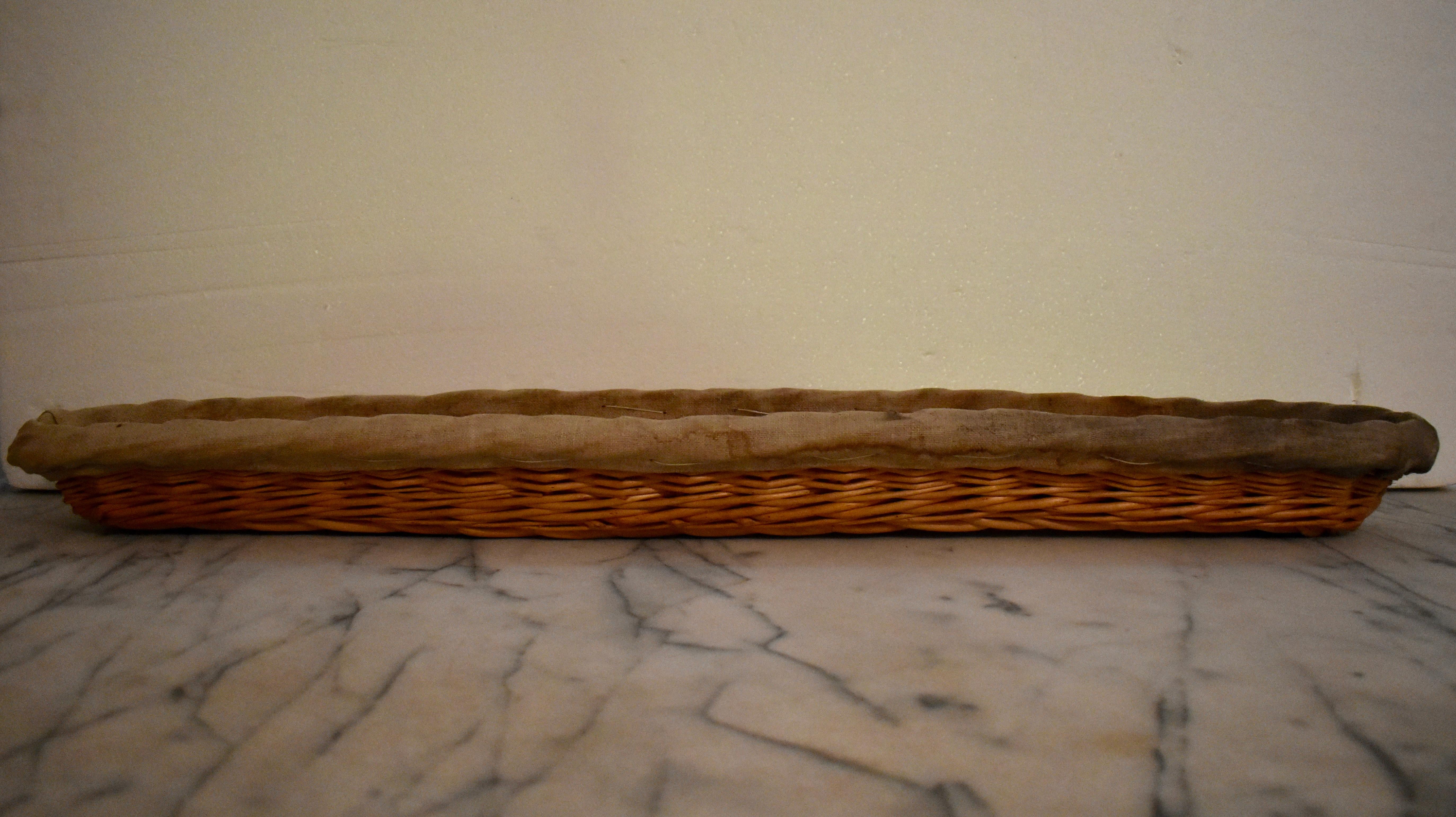 A rustic antique Boulangerie baguette proving basket with a linen liner, known as a banneton, from Brittany, France, circa early 1900s.

Nearly 33 inches long, these baskets were used in bakeries or boulangeries throughout France. The willow basket