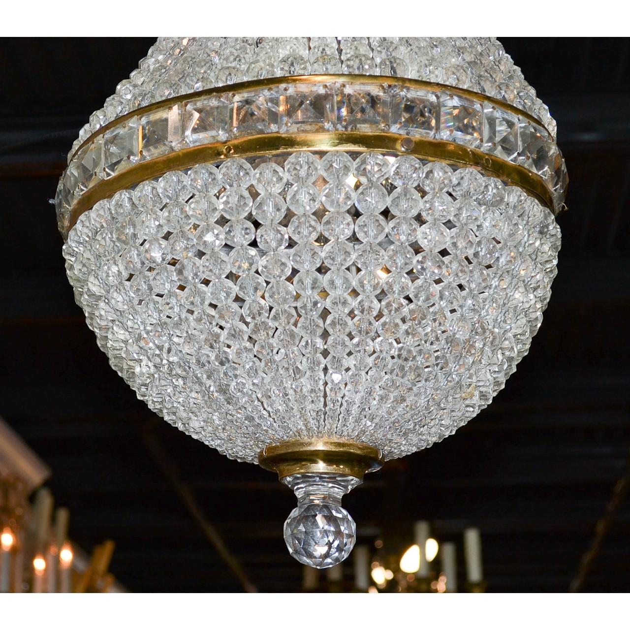 Elegant early 20th century French gilt bronze and crystal basket chandelier. The crown and central band inlaid with square baguette cut crystal prisms. The entire with multiple strands of cascading bead crystals. The base accented with a faceted