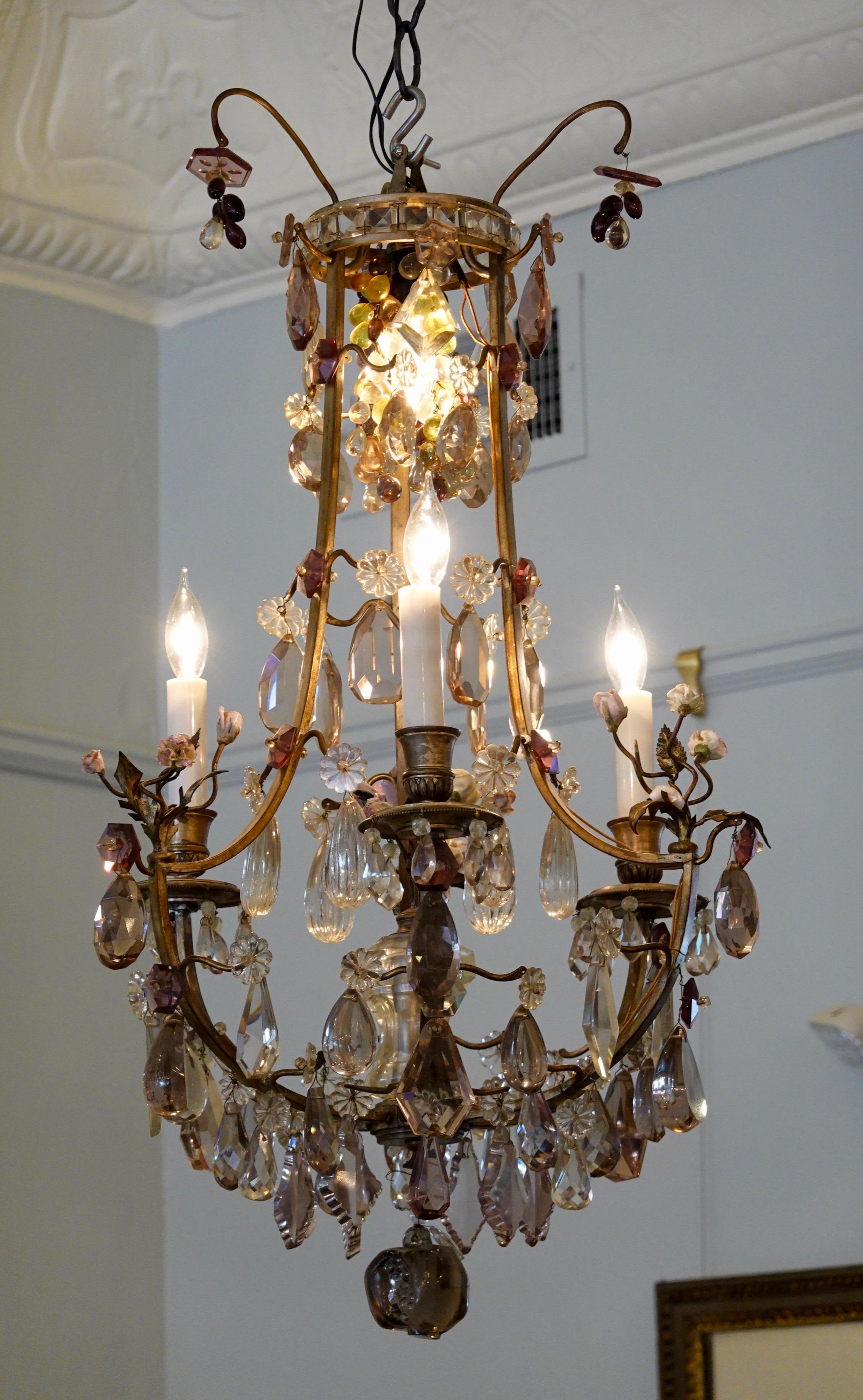 French cage-form bronze and crystal chandelier with porcelain flowers in the Louis XVI style, electrified with four lights. This chandelier features three bunches of porcelain flowers on the main arms, with a central spray of porcelain flowers in