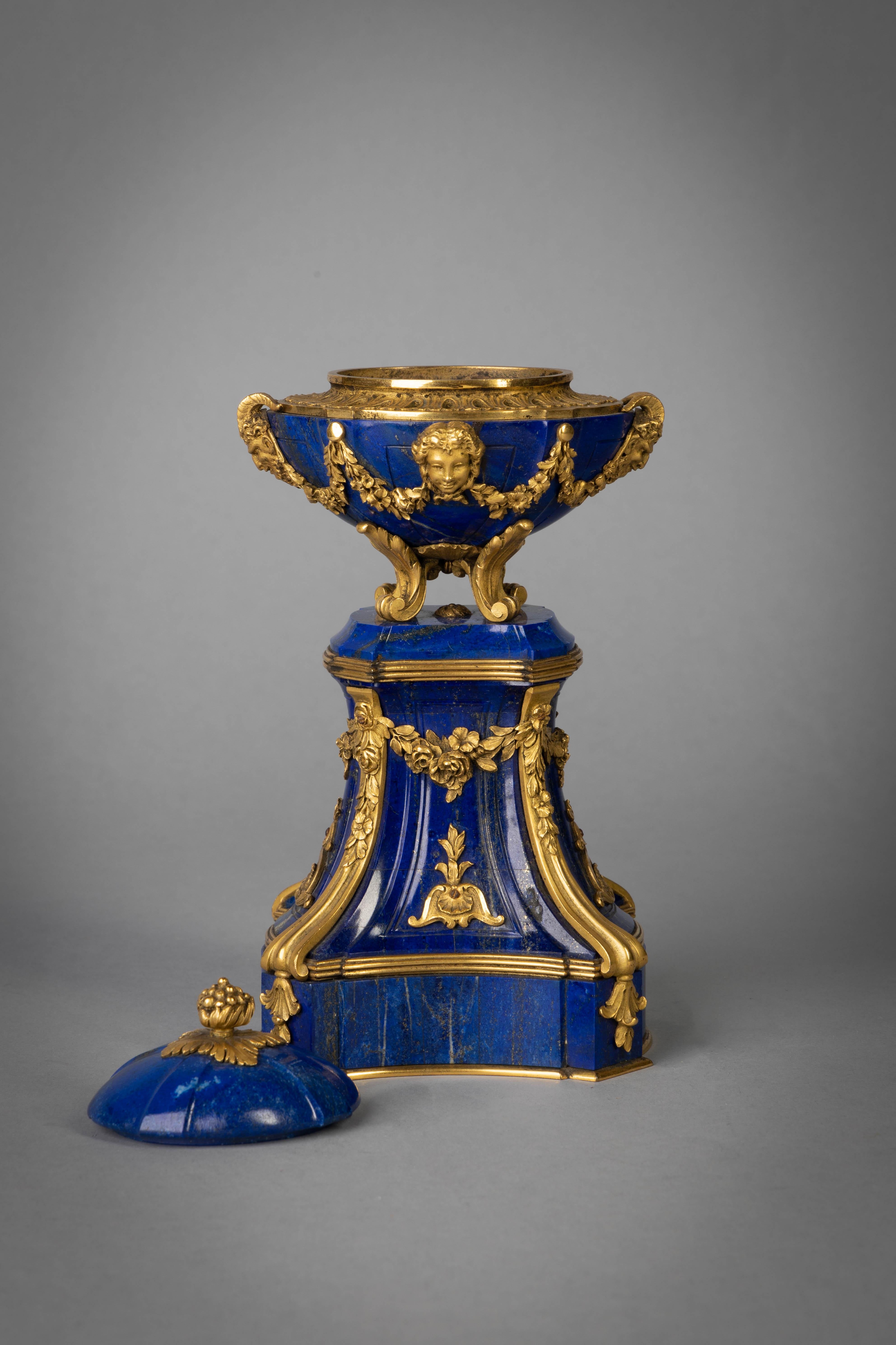 With rich lapis and jewel-like bronze mounts, satyr mask handles and garlands of flowers centered on two bacchantes. The pedestal similarly mounted with garlands and shells.