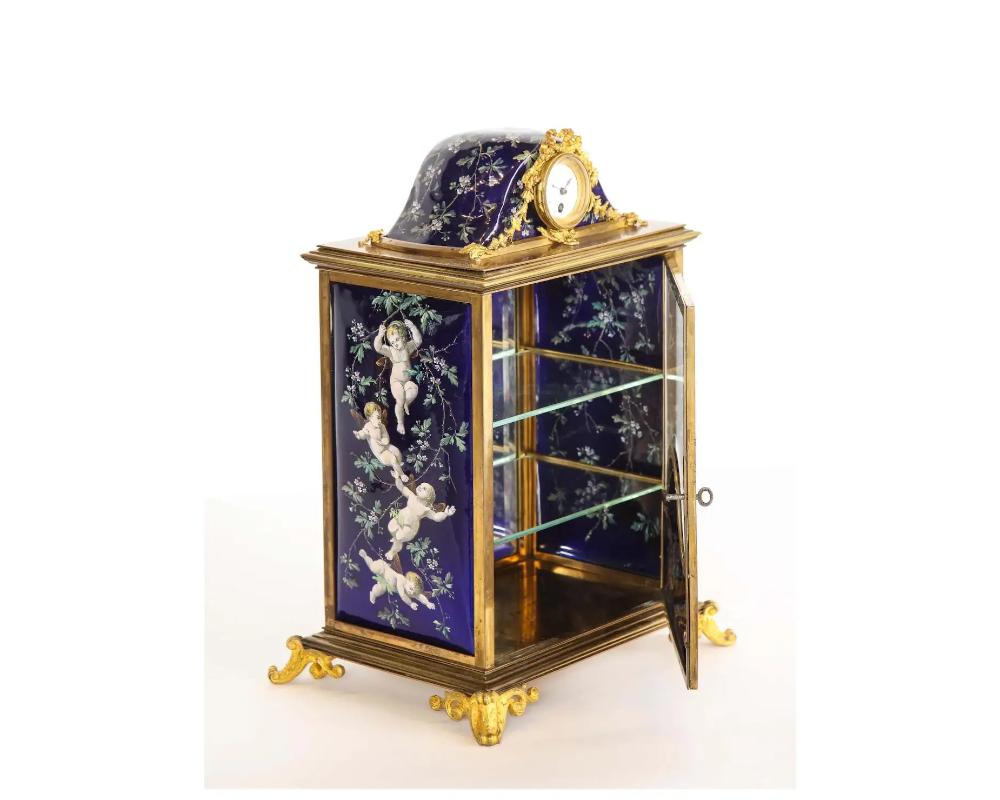 A french bronze and limoges enamel jewelry vitrine cabinet with clock, 19th century.

hand painted with beautiful cobalt blue panels of cherubs. The door opening to glass shelves, and mirrored glass with original key.

The top, with an original