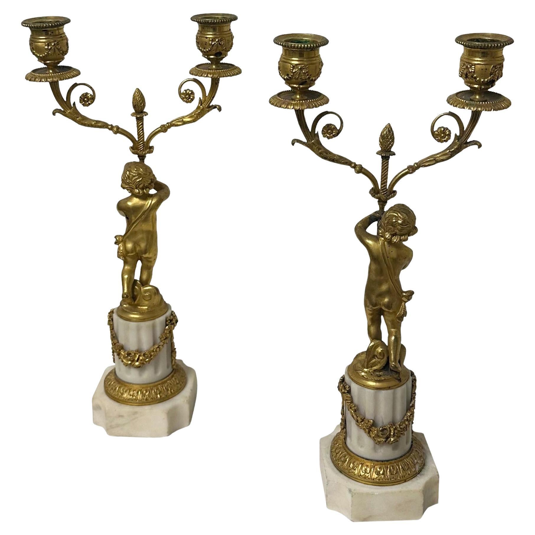 A very elegant pair of early 19th century bronze and marble candleholders with putti, an acorn, swags and bows. 