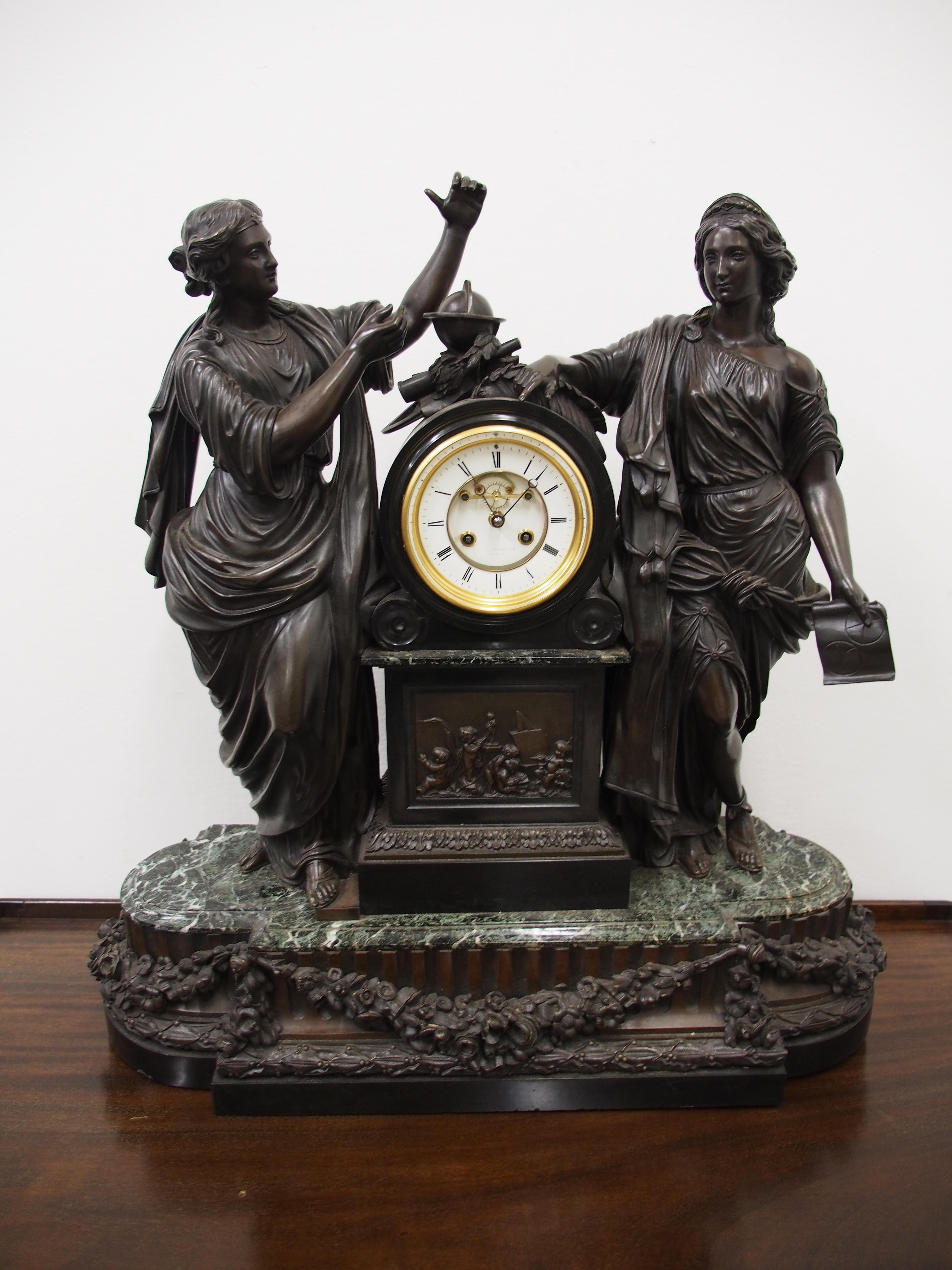 Large French bronze and marble clock garniture emblematic of literature, circa 19th century. The white enamel Roman number dial has an exposed escapement, set in a column surmounted by a trophy representing the arts. The clock is flanked by standing