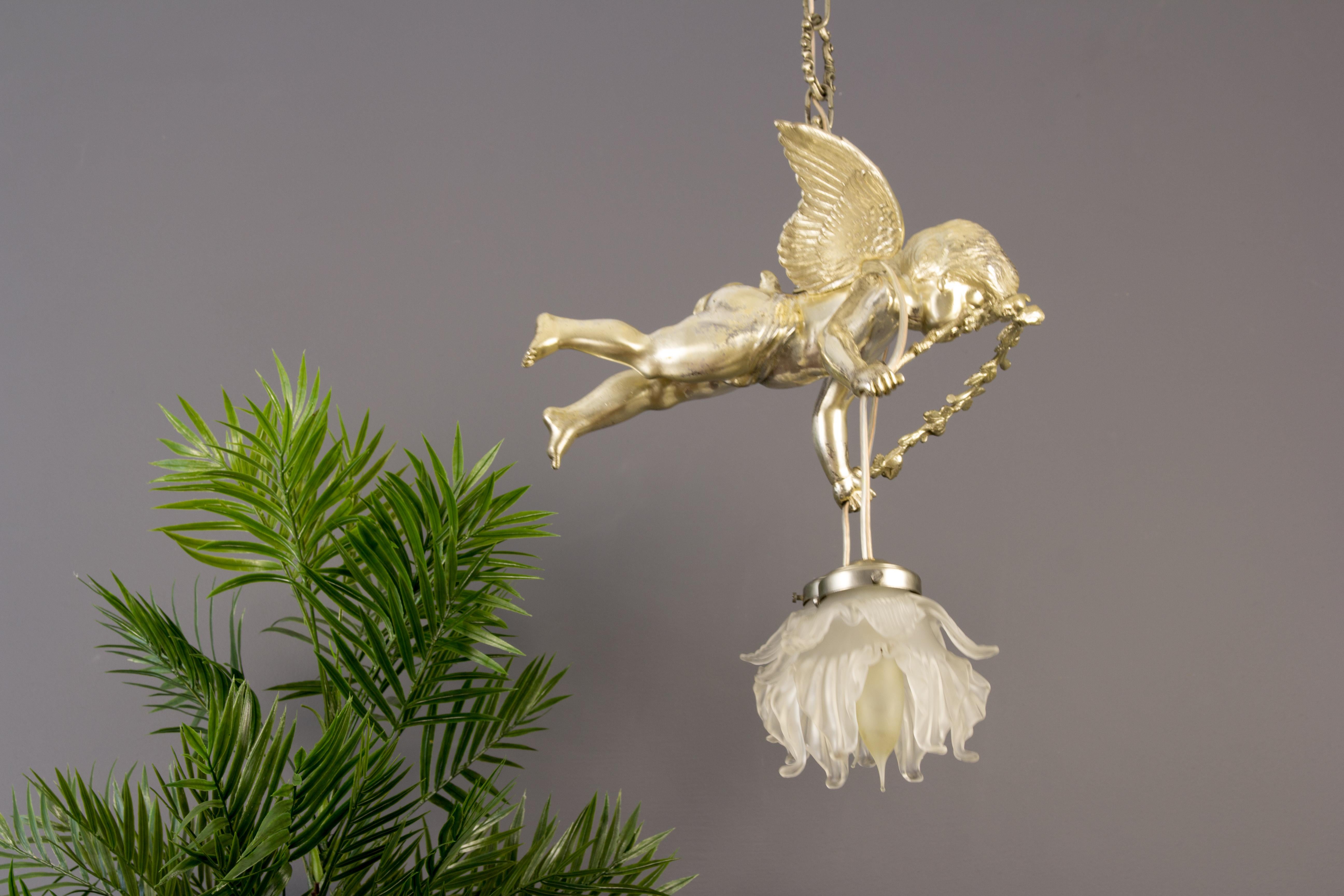 Beautiful light fixture or chandelier with large winged cherub figure, holding flower garland ending on two lights with flower-shaped frosted glass shades each with a socket for E14 light bulb. France, circa the 1920s.
Measures:
Cherub:
Height: 25