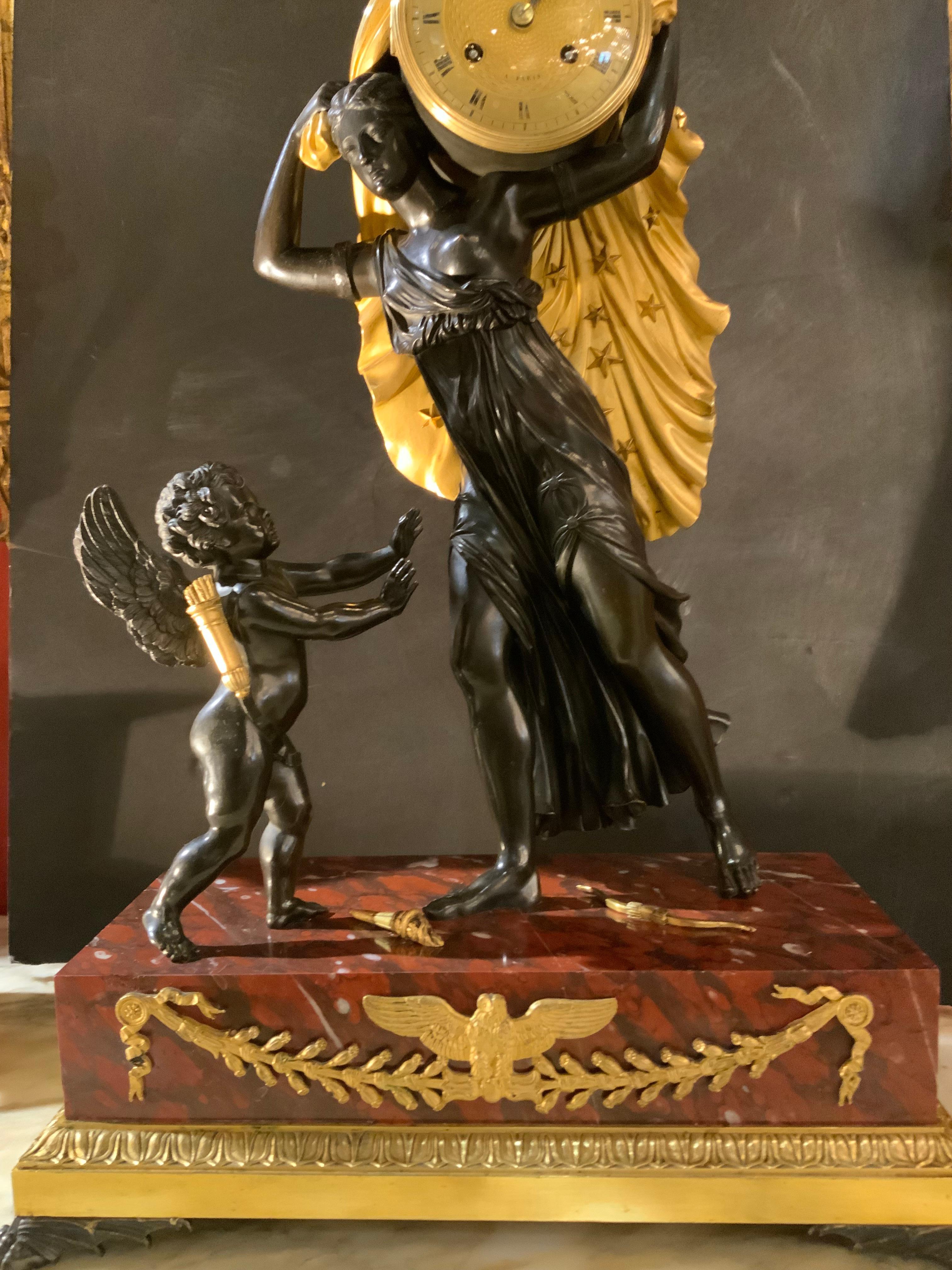 This fine clock is made  by the French bronzier thomire
It depicts a story about Aurora  which is the advisary 
Of Amor. She stops darkness by pulling the star studded cloak 
From the world. Amor tries to stop her from going forward.
This symbolizes