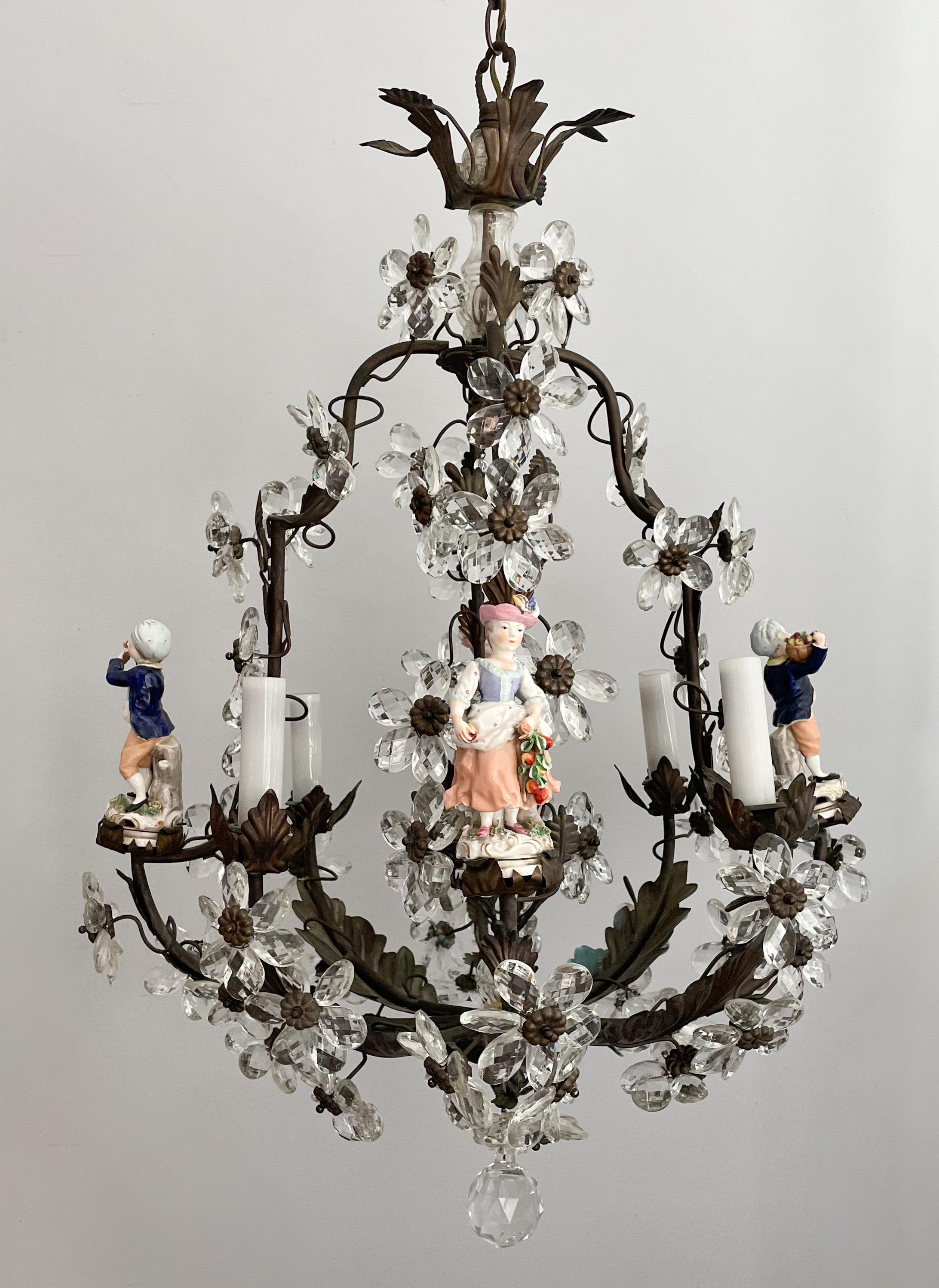 Gorgeous, French 1940s bronze, crystal and porcelain chandelier in the provincial style.

The chandelier consists of a bronze frame decorated with an abundance of flowers made of faceted crystal prisms and porcelain figurines.

The chandelier is