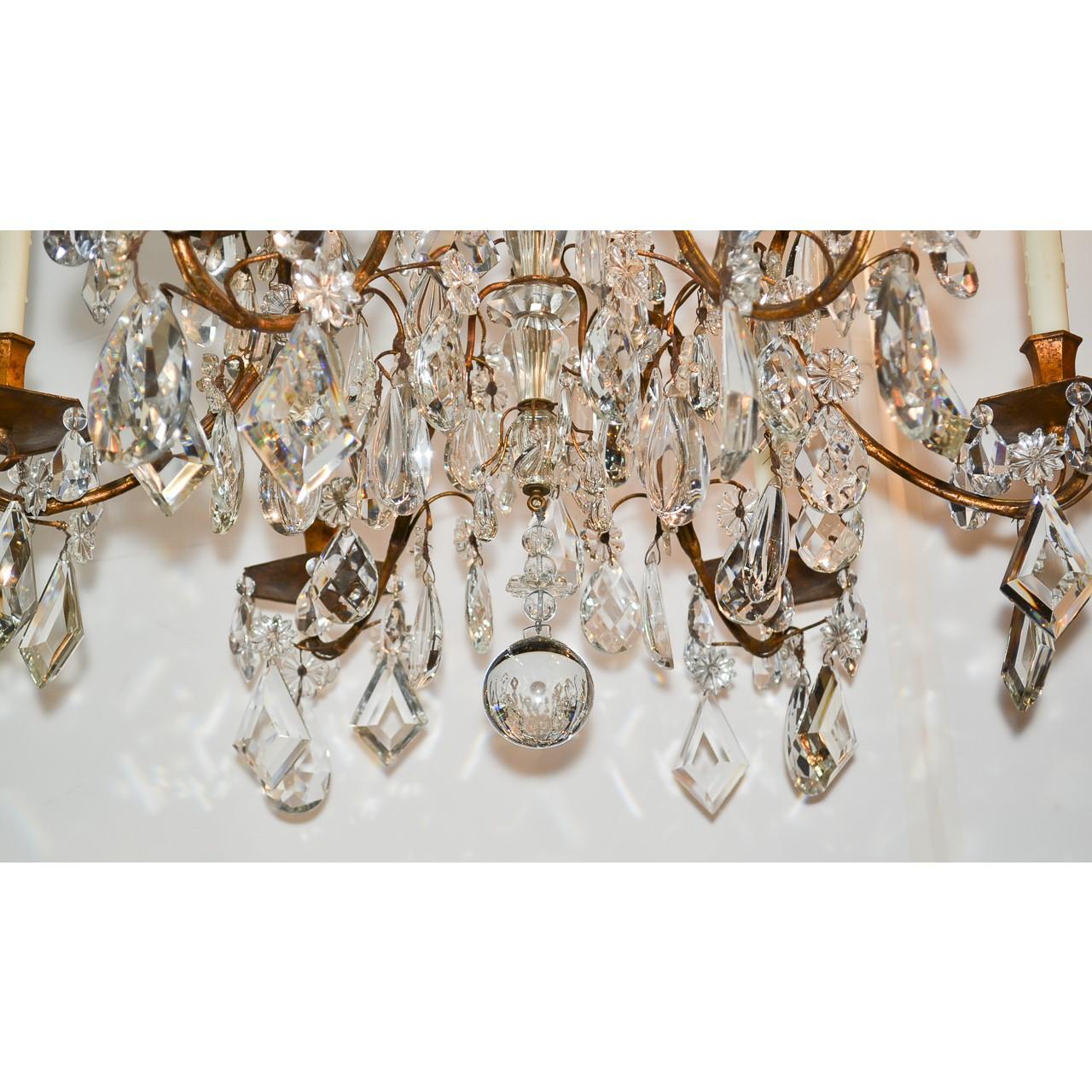 Stunning high style French gilt bronze and crystal chandelier. Lavishly decorated with multiple graduated tiers of fancy crystals, including almond, tear-drop, kite, and diamond prisms. Accented with an abundance of crystal rosettes and having an