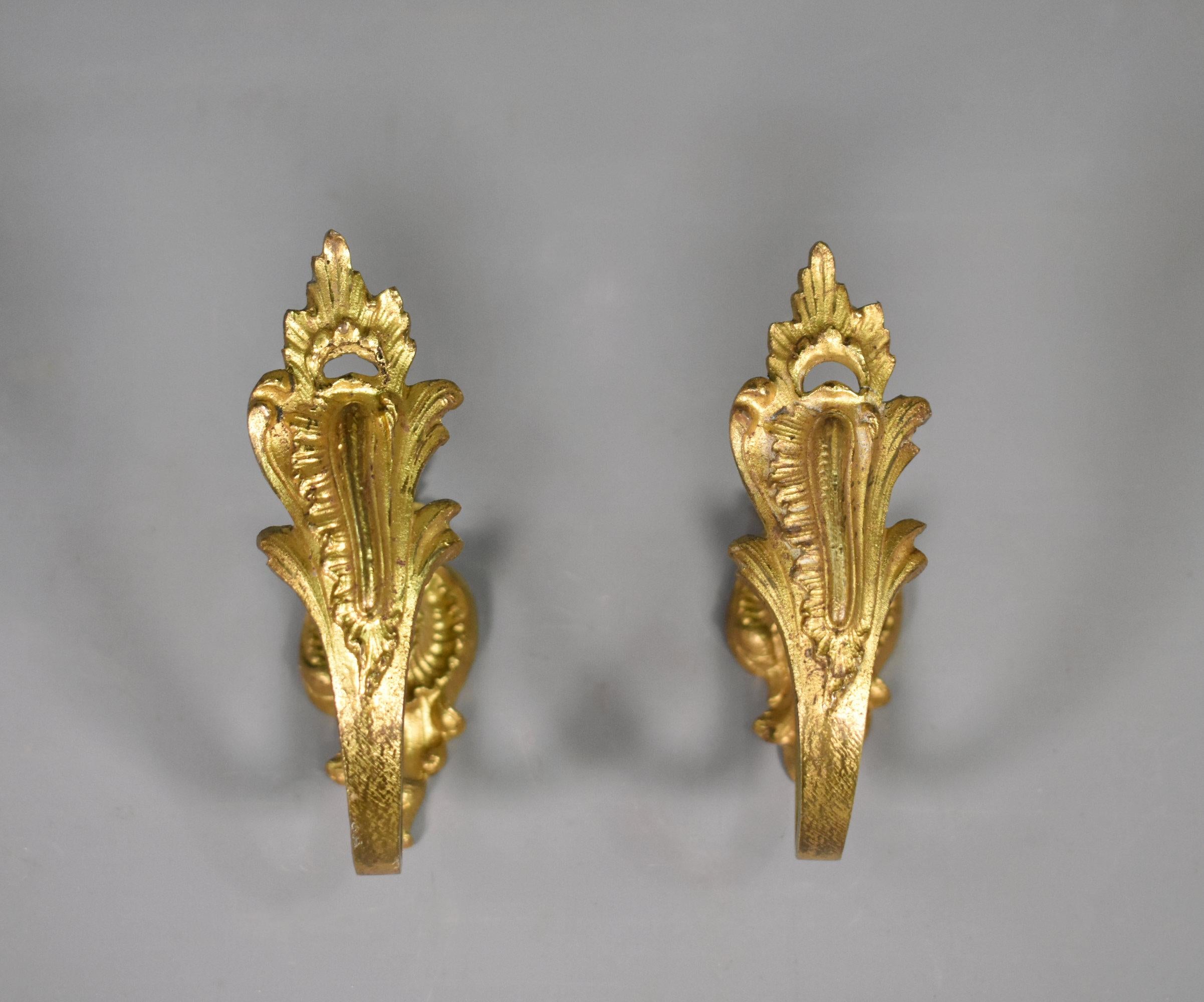 Embouts de rideaux en bronze de style Louis XV 

Cette élégante paire d'embrasses de rideaux en bronze doré présente un décor de feuilles d'acanthe et de coquillages. 

Ils sont suspendus à la plaque arrière et sont épinglés au mur dans la partie