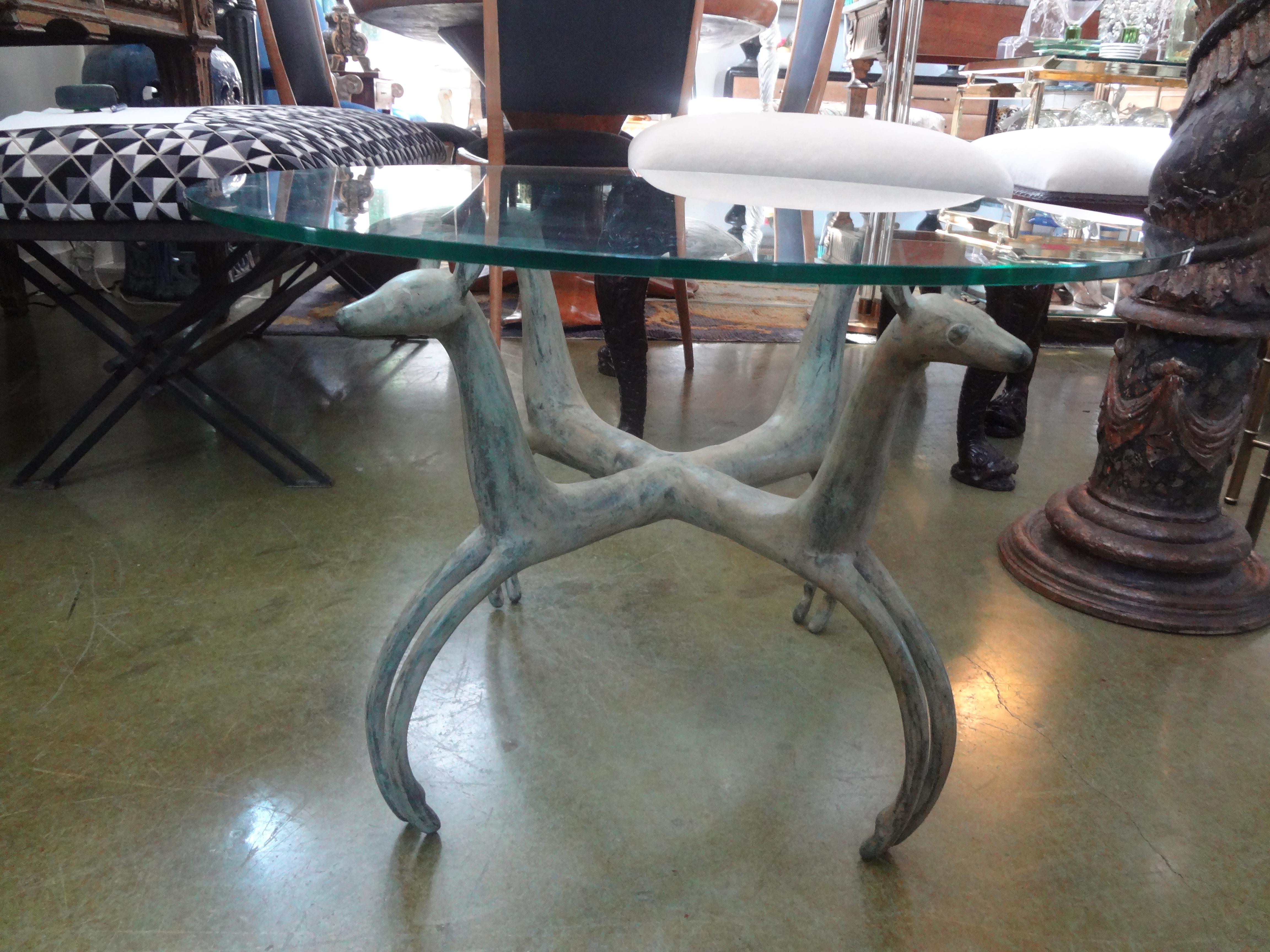 French bronze deer table After Armand-Albert Rateau. This stunning French Art Deco revival table is comprised of four patinated bronze deer with a glass top. This bronze base can support a much larger piece of glass as needed. Or used as a side