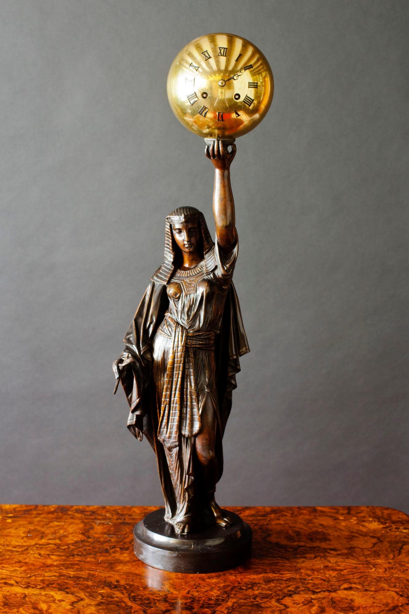 French Bronze figural clock with a finely cast Bronze statue depicting Aurora holding a brass Orb clock with Roman numerals and original moonpoise hands. 
 
Eight day French movement striking the hours and halves on a silvered bell. Numbered 237