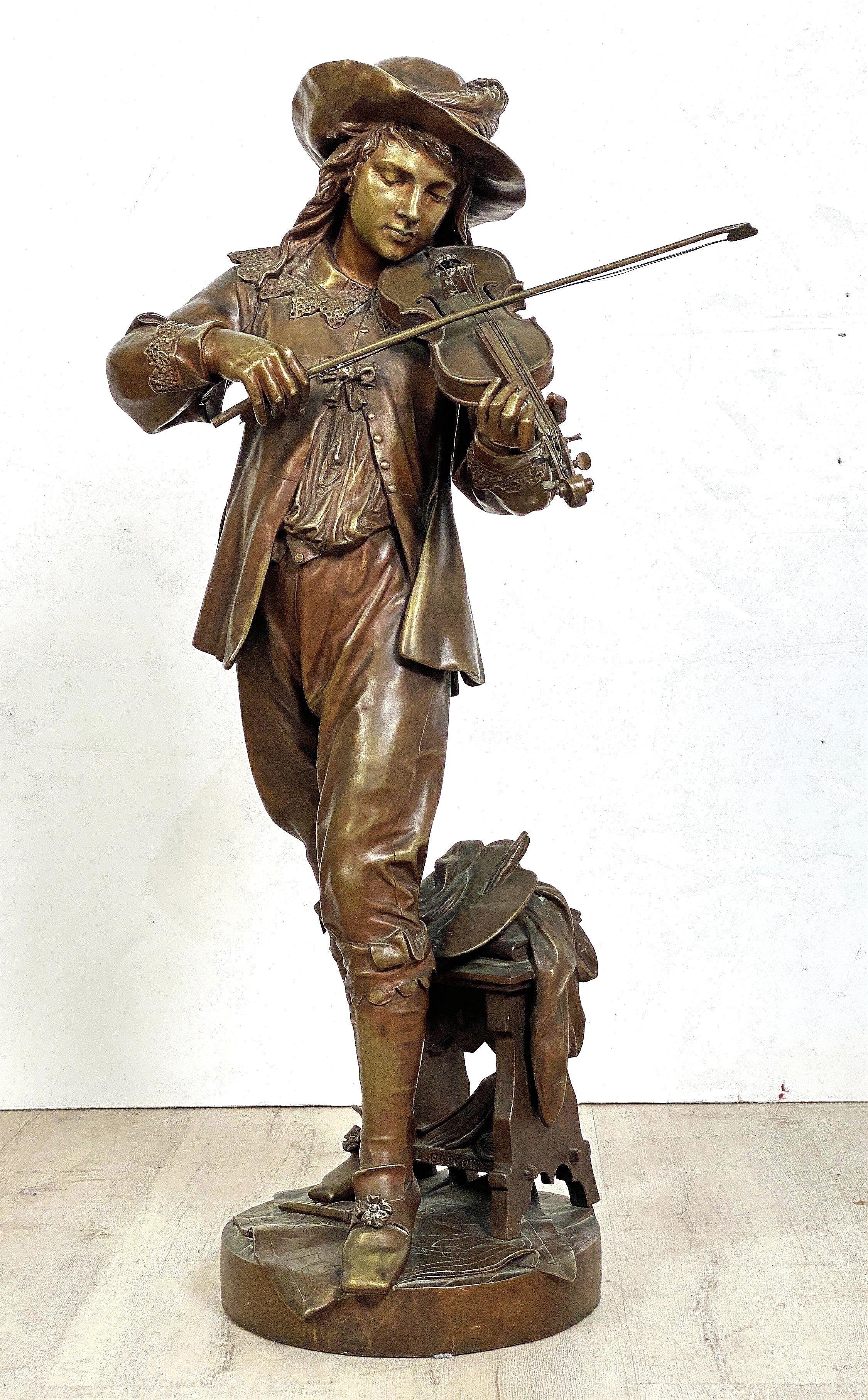 A large French bronze sculptural figure of a musician -in the round - from the late 19th century, featuring a man in fancy dress playing a violin or fiddle, set upon a round raised plinth base.

Signed to the base 