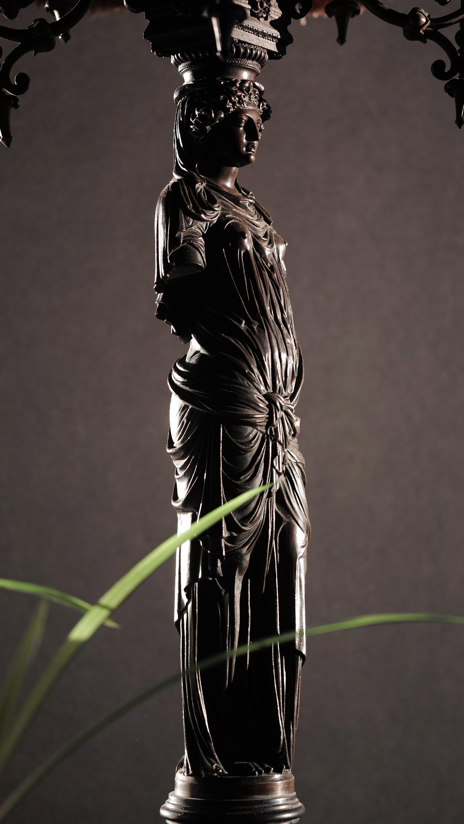Wir bieten Ihnen diese französische Bronze-Réduction Mécanique der Karyatiden von Jean Goulon im Louvre an. Die Bronze ruht auf einem schwarzen Marmorsockel und wird von einem Kandelaber mit Holzimitatkerzen gekrönt. Der geraffte Stoffschirm hat