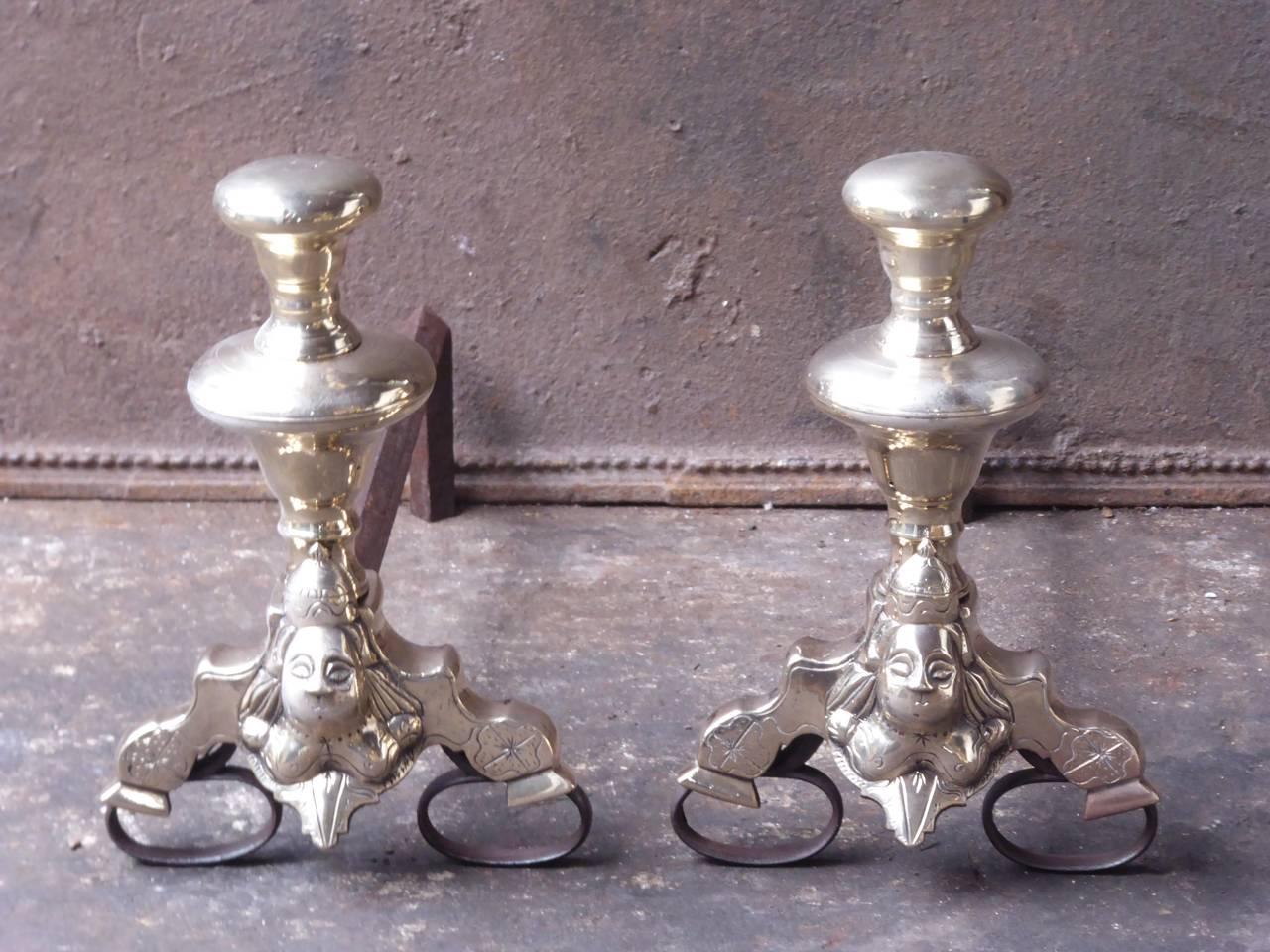 A pair of medium-sized 17th century French Louis XIV fire dogs made of polished bronze and wrought iron. The faces on the andirons are so-called marmosets. A marmoset is an ornamental motif representing a small figure in a burlesque or extravagant