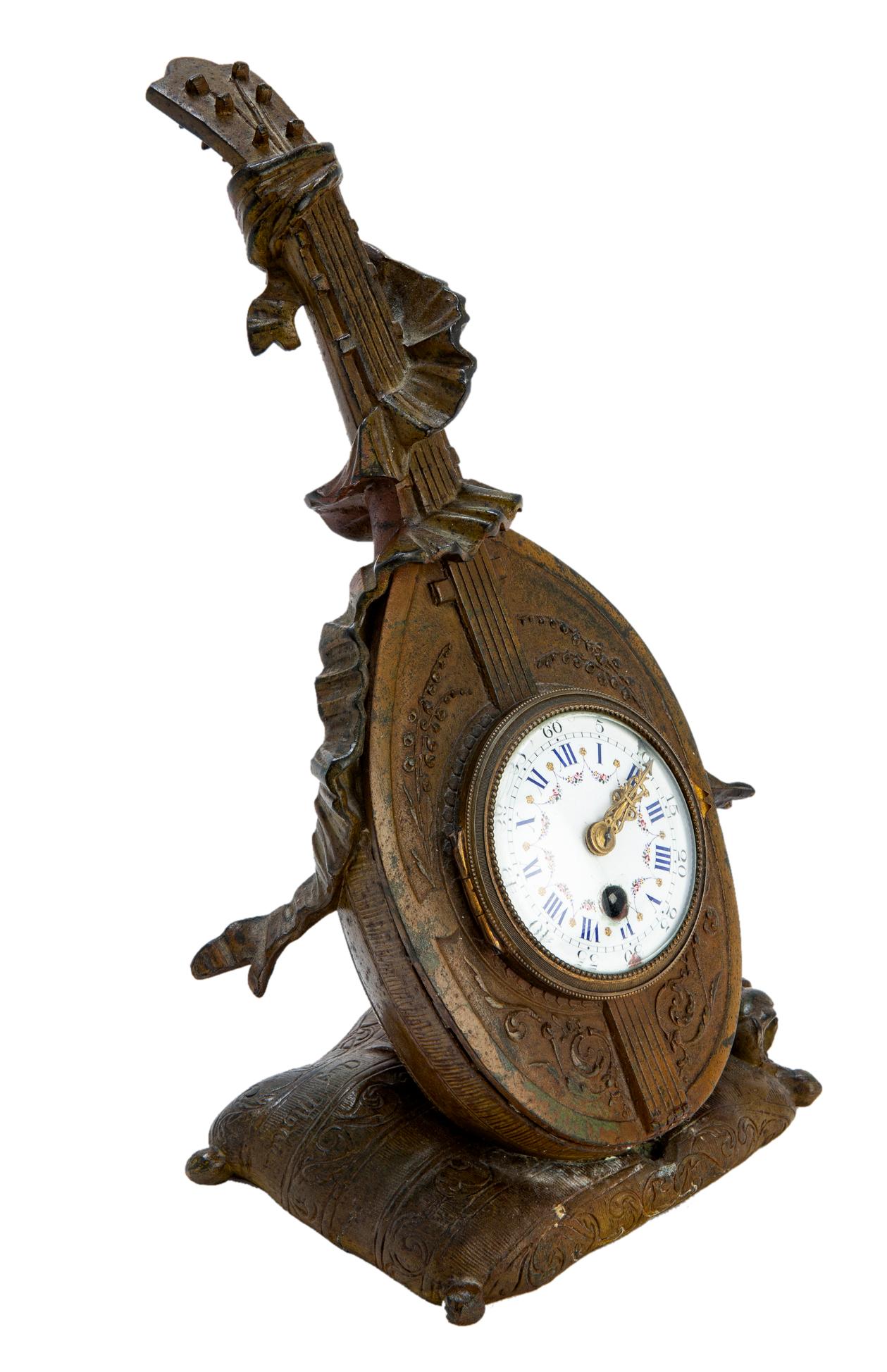 Une petite horloge de table en bronze, avec un cadran en porcelaine finement peint à la main, des aiguilles et des accents dorés. Il est très probable que le bronze ait été doré au moment de sa fabrication, mais que la dorure ait été enlevée lors du