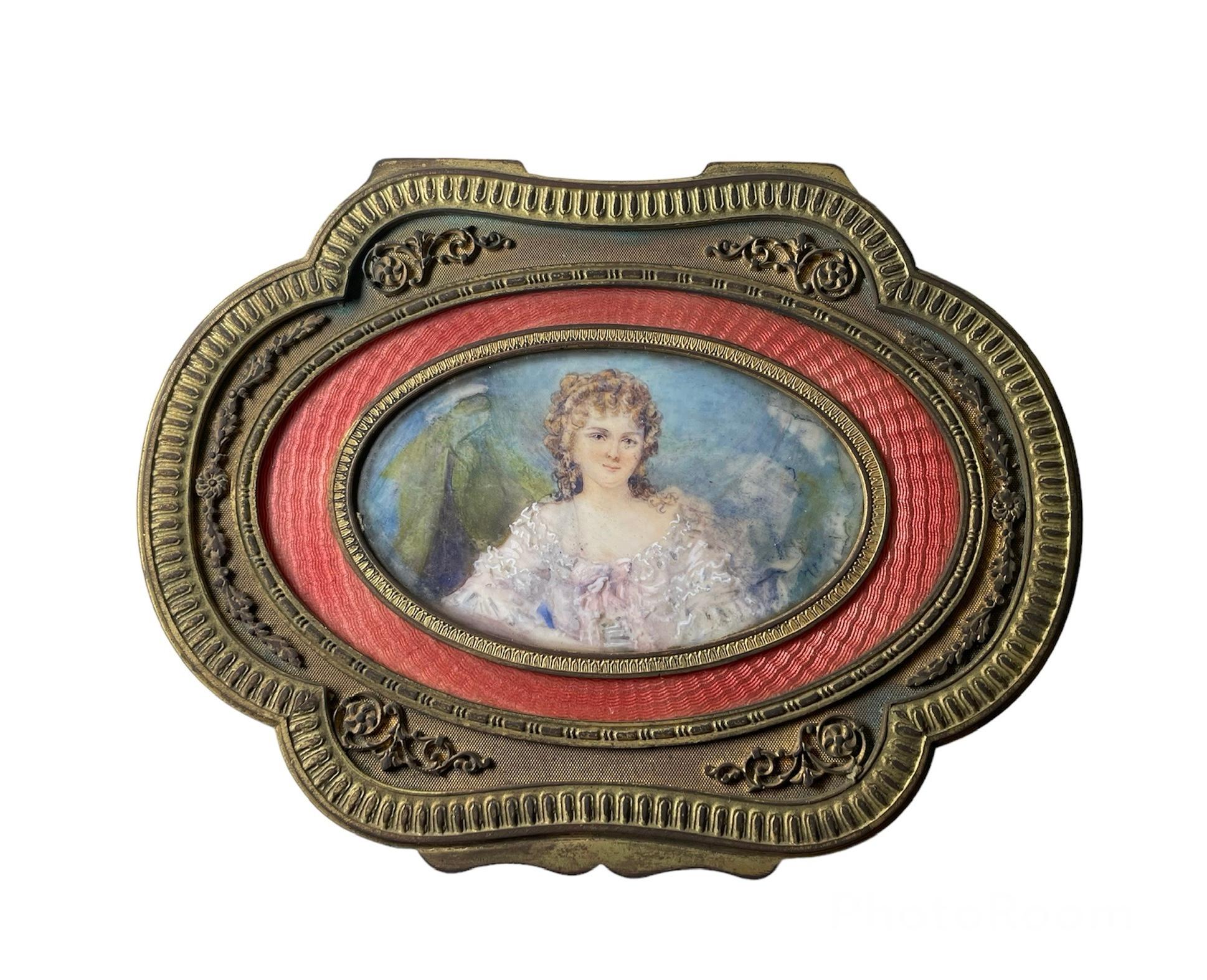This a French bronze metal hand painted portrait vanity box. It depicts a quatrefoil shaped hinged lid that is decorated in the center with the portrait of a young lady. An orange color guilloche inset panel framed the portrait, then a relief of