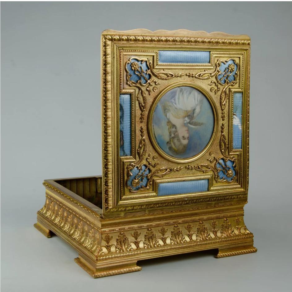 French Bronze Miniature Portrait Jewelry Box
Beautiful rectangular French jewelry box
with hinged lid with a centered miniature depiction of a lady, flanked by elongated, oval glass panels, opening to a fabric-lined compartment, raised on block