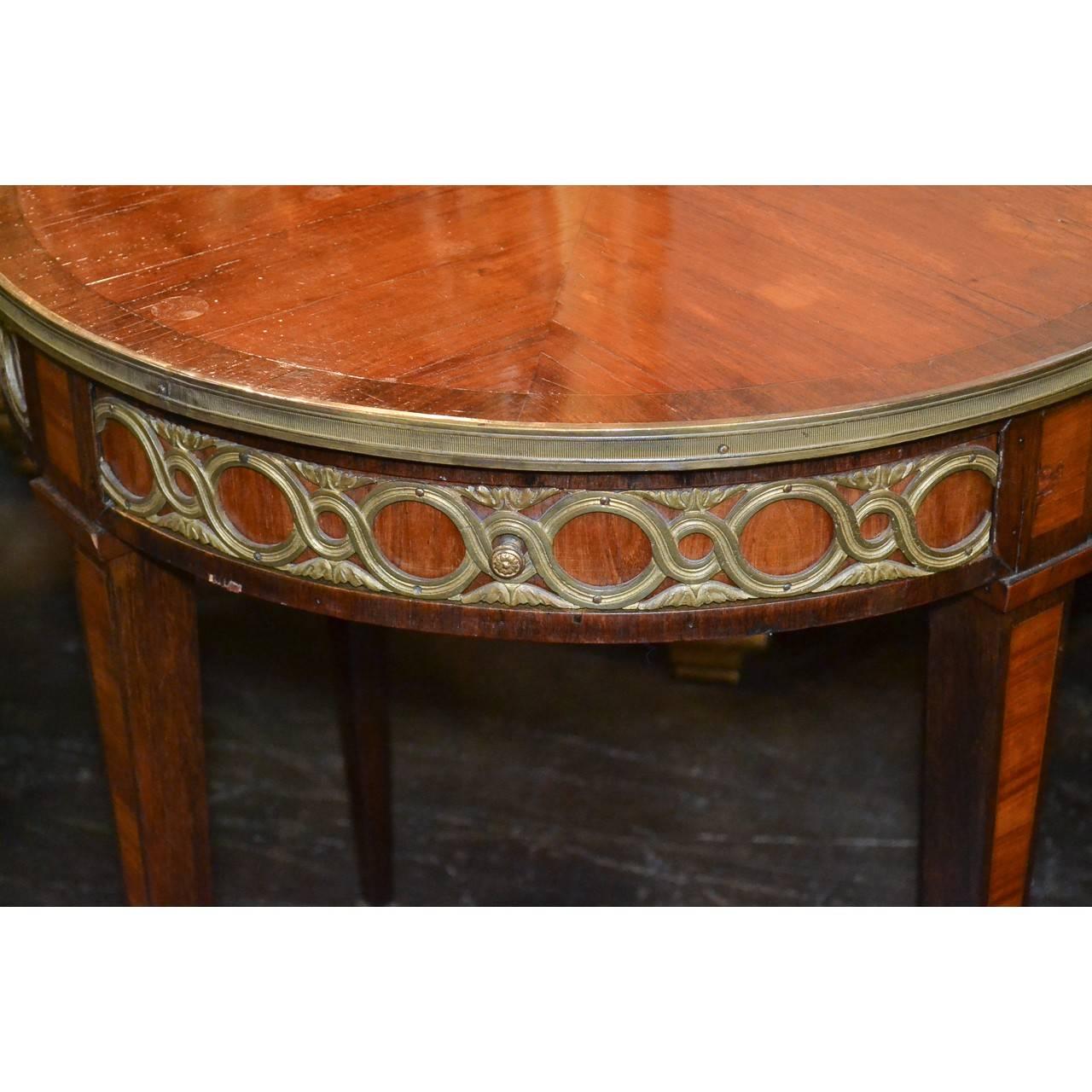 Exquisiter runder französischer Beistelltisch oder Bouillotte-Tisch aus Königsholz und Palisander aus dem 19. Jahrhundert mit einer ausziehbaren Getränkeschublade mit Ledereinlage. Der Fries ist rundherum mit stilisierten Doré-Bronzebeschlägen