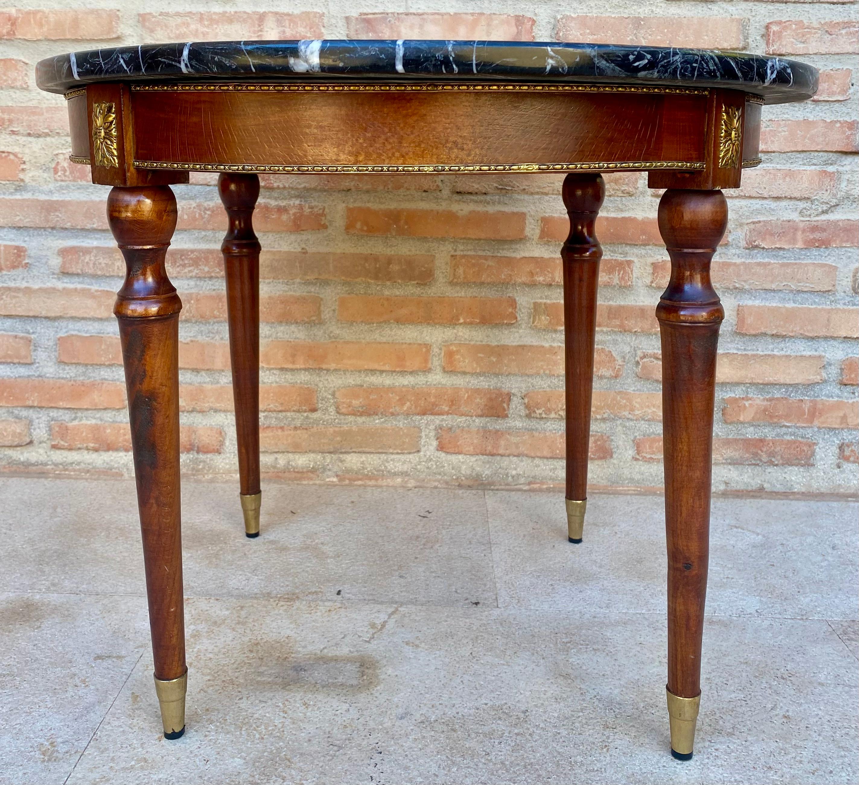 Side, central or sofa table with black marble top with white veins. This finely crafted walnut wood side table has elegant tapered legs with a brass frame that supports a black marble tabletop with a brass gallery. The table is supported by bronze