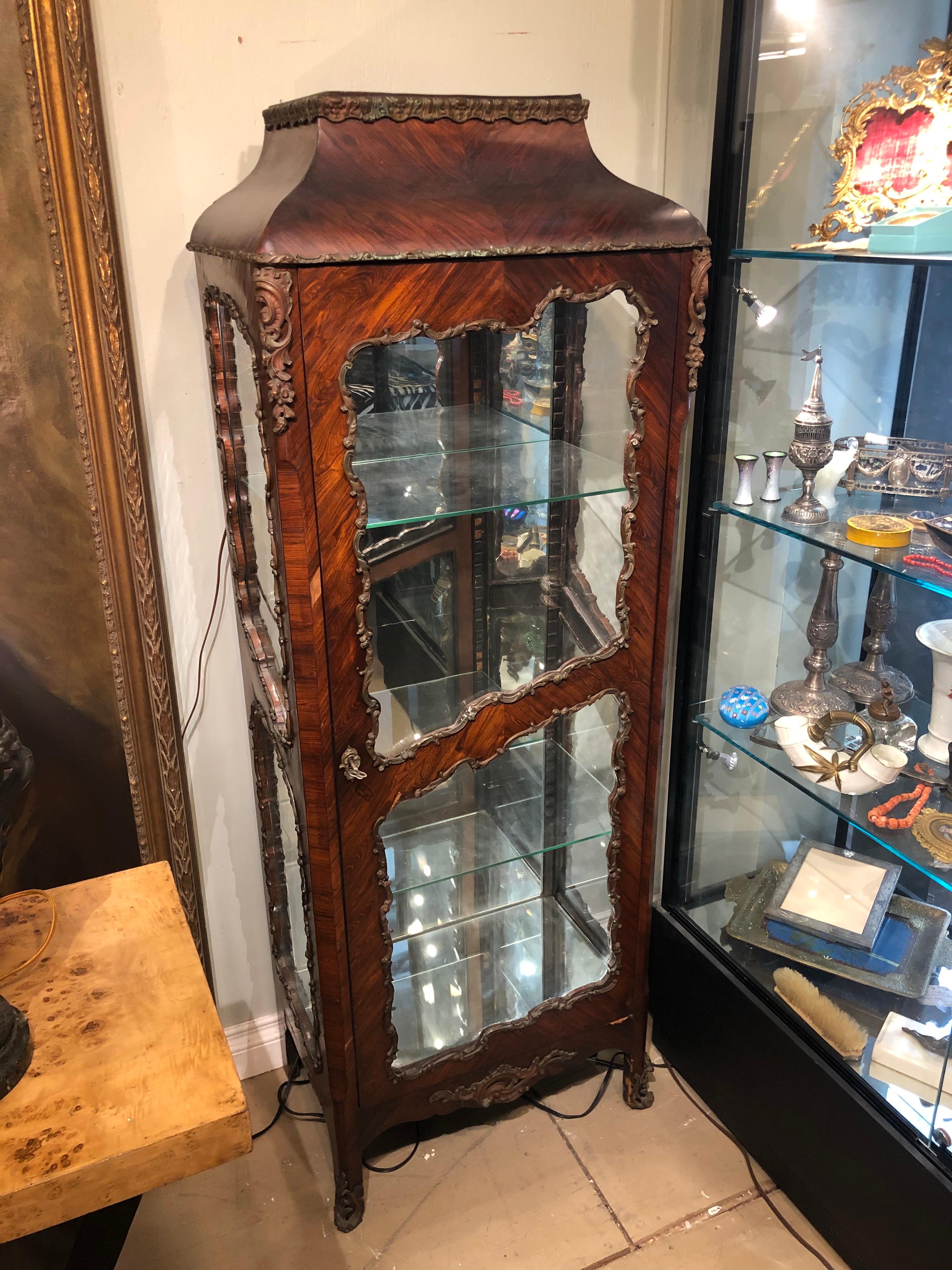Circa 1900 French bronze mounted mahogany vitrine, In the Louis XVI style, with 3 sides of glass panels and the original lock and key. The electrics has been updated and the interior lamp works perfectly.