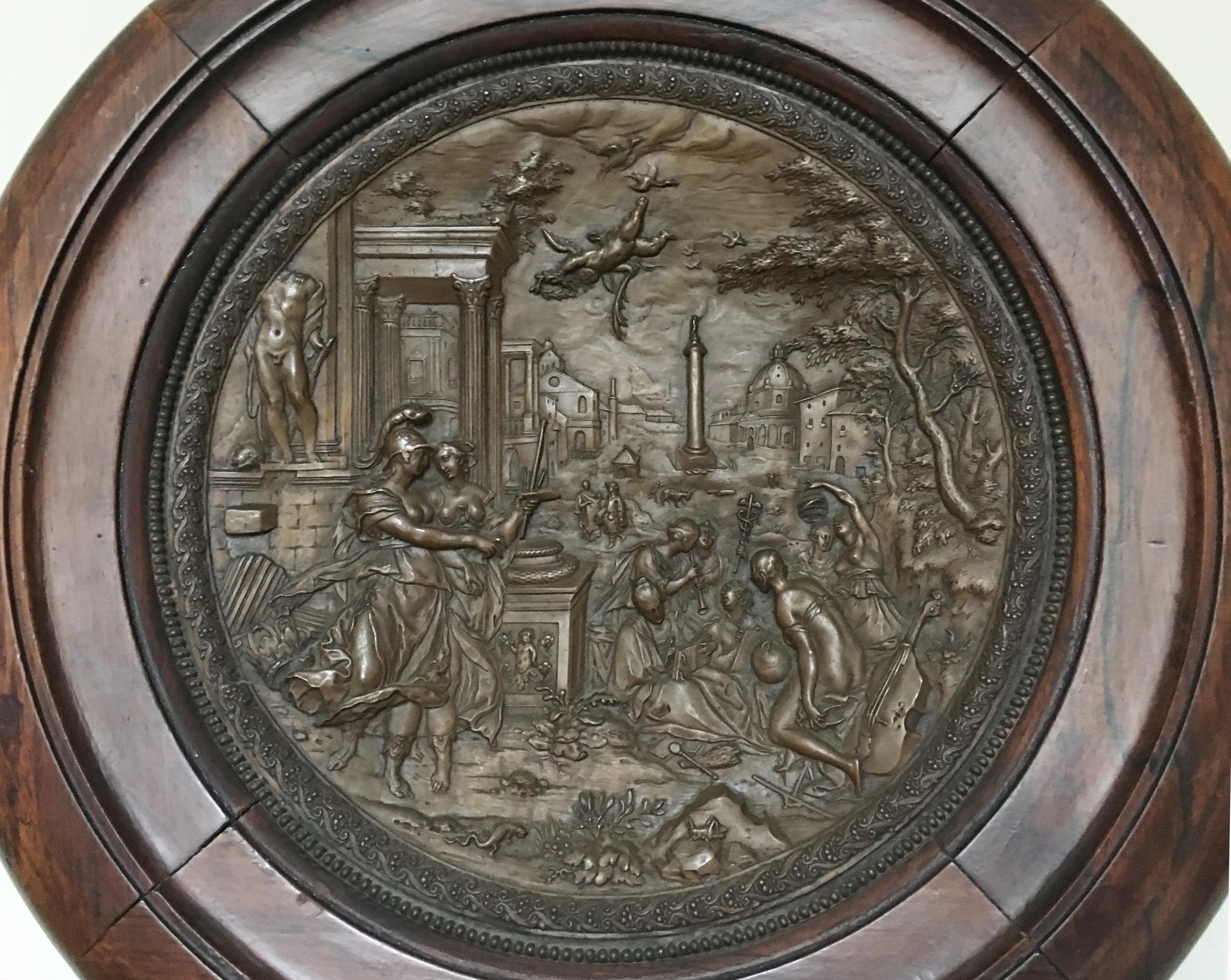 Extremely fine French bronze repousse wall medallion sculpture.
Late 19th century.

Bronze repousse medallion depicting a Roman city scene of civilians in the courtyard, near a Roman Centurion courting a maiden, cupids flying overhead, with