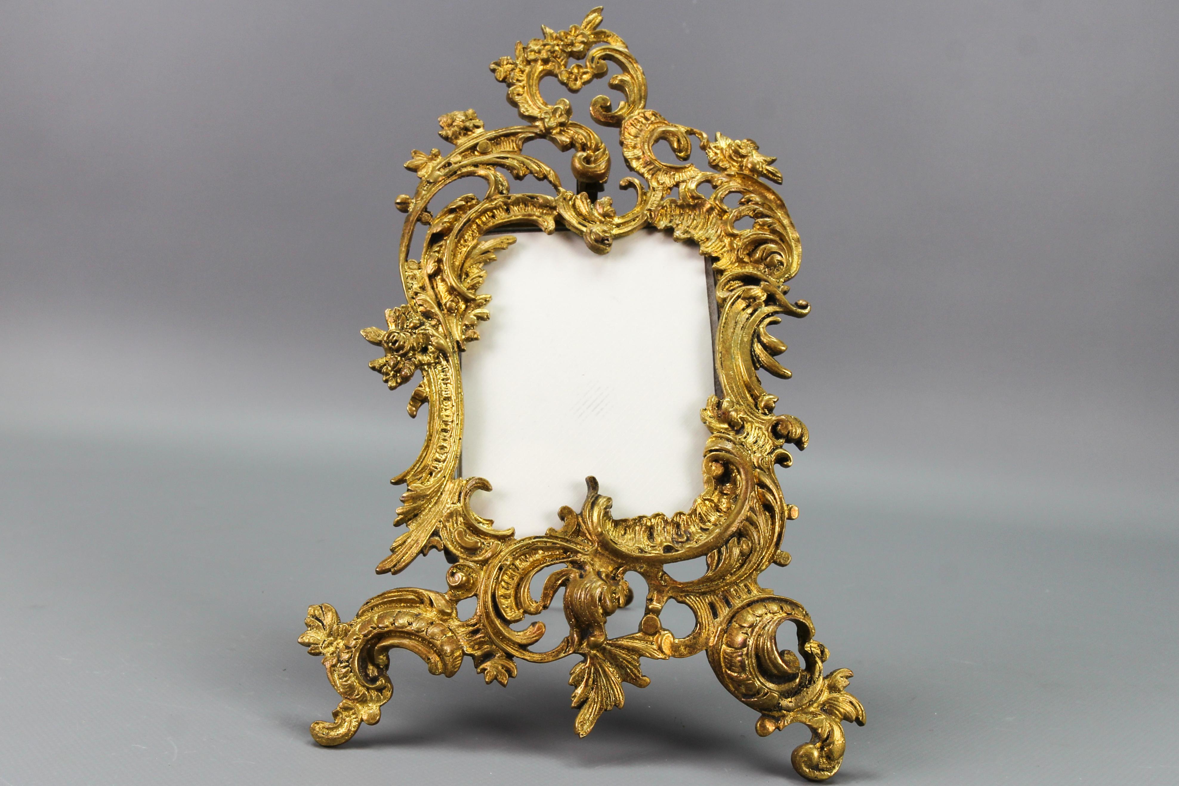 French Rococo-style bronze photo or picture desktop easel frame from circa the end of the 1920s.
This magnificent ornate frame is made of bronze and has an easel supporting leg on the back. Decorated with typical Rococo or Louis XV-style scroll,