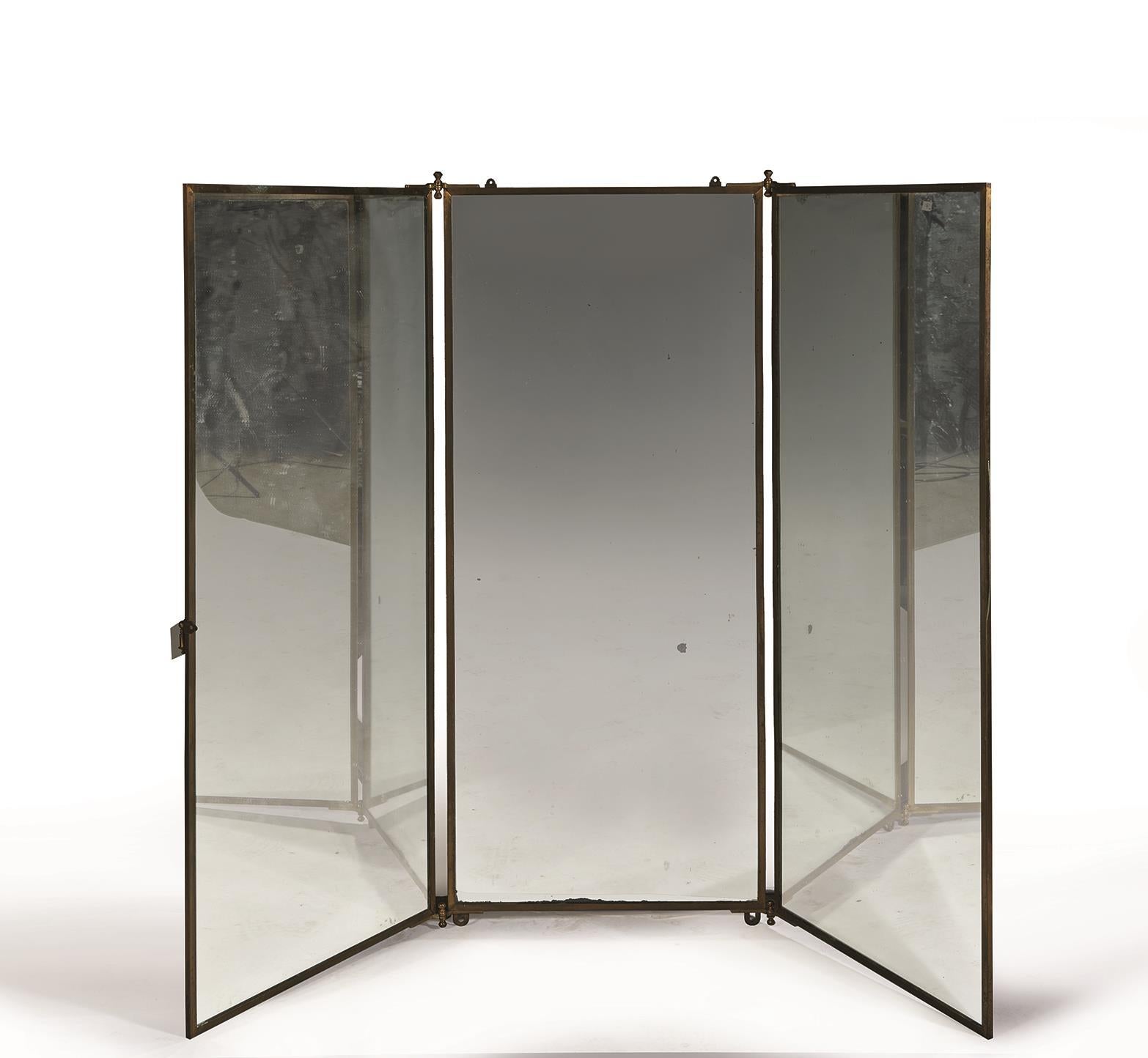 Brot Miroirs (Established 1826).
A dressing mirror, circa 1940.
Three folding panels in a brass frame, with two wall fixtures to the top of the central mirror.

Each panel: 51 1/4 in. (130 cm.) high; 21 3/4 in. (55 cm.) wide 
The whole,