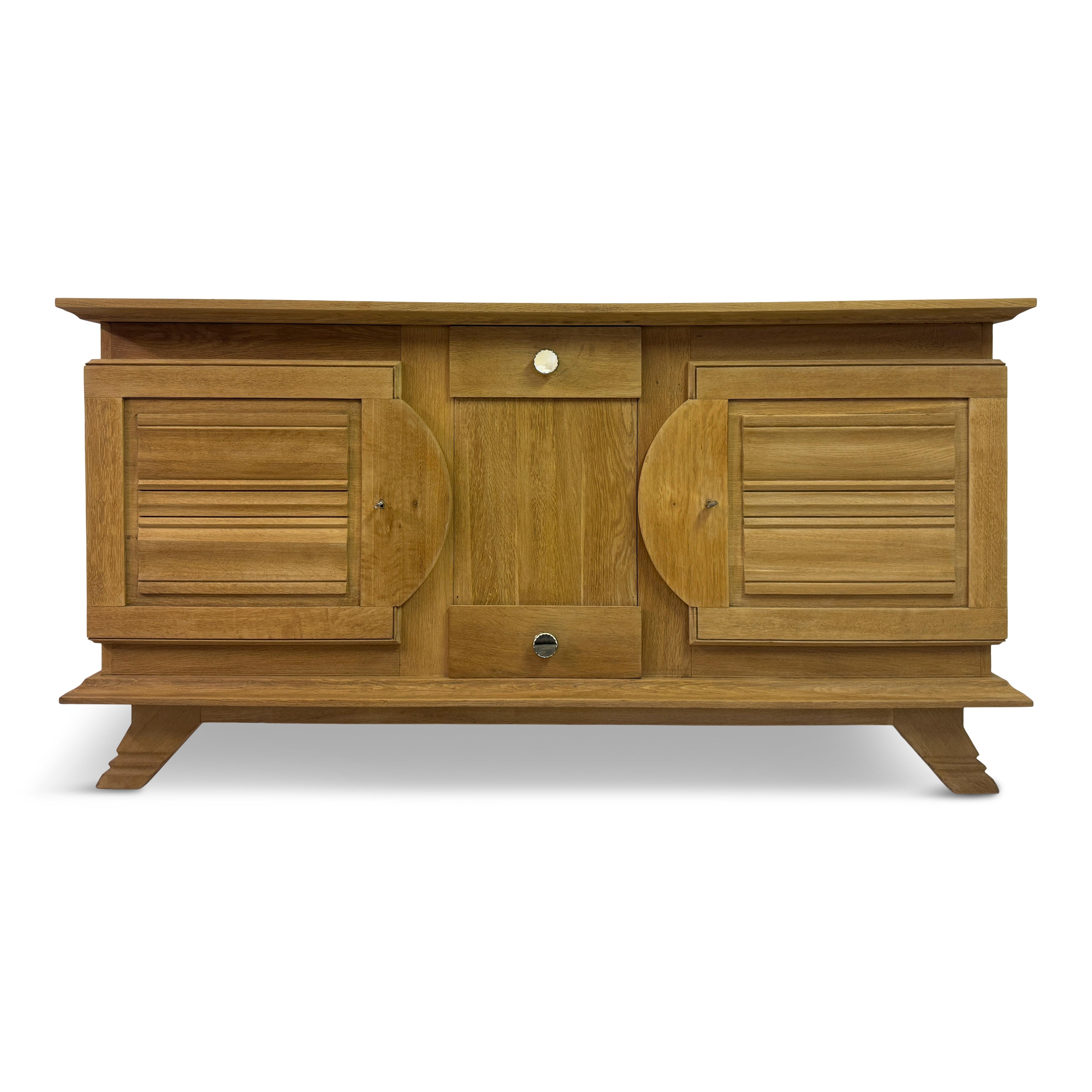 Ce buffet est un exemple remarquable de la fusion des styles brutaliste et Art déco des années 1930-1940. Construite en chêne massif, cette pièce présente une esthétique robuste et terreuse qui met en valeur la beauté naturelle du grain du bois.

La