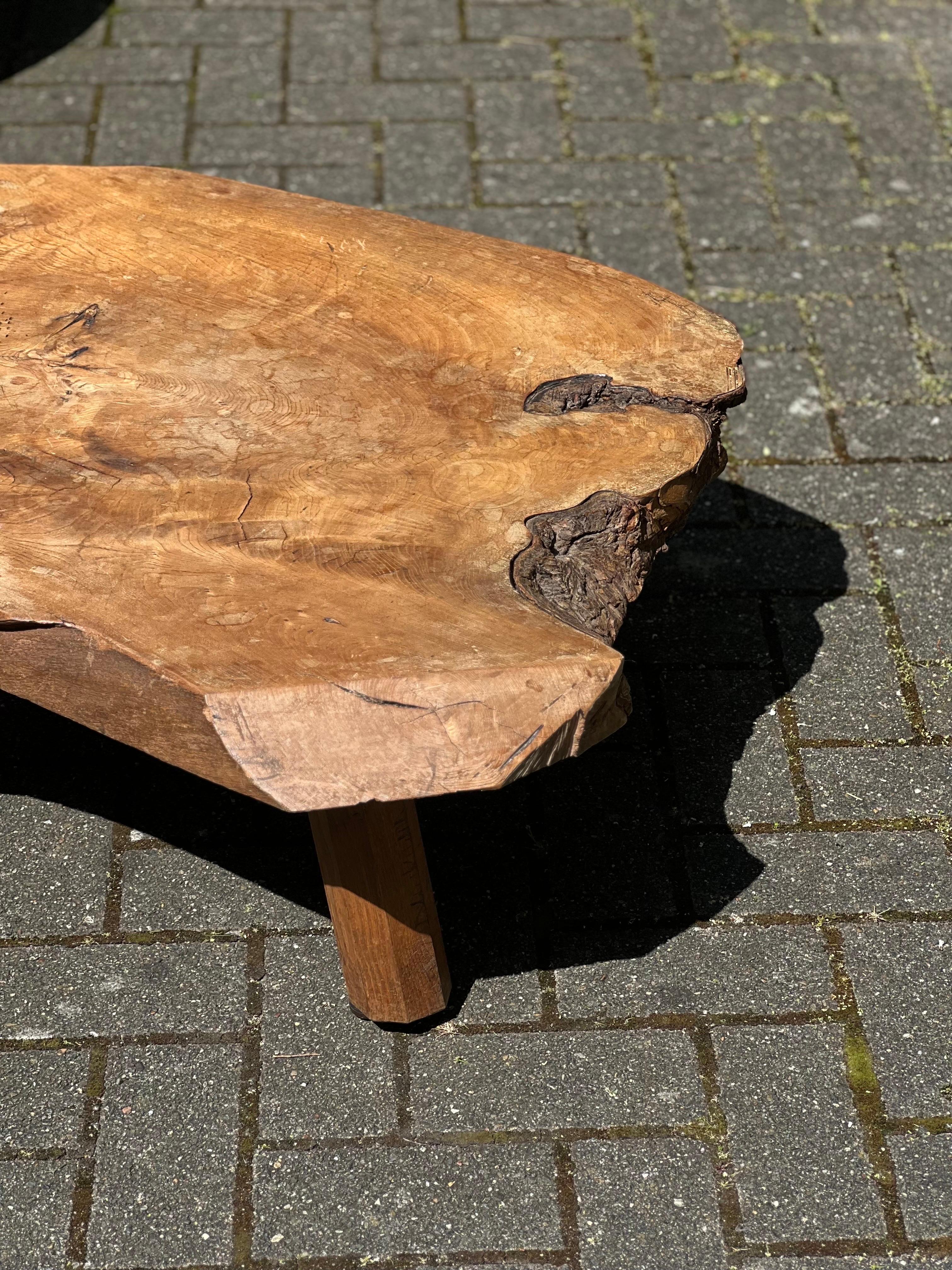 Very unique oak handmade massive slay of tree. It is a free form shape. The top is patinated and shows various shades of brown/brownish colors and honey tones. Elegant and brutalist describe that table properly. The height is 31.5 cm and is 86 cm x