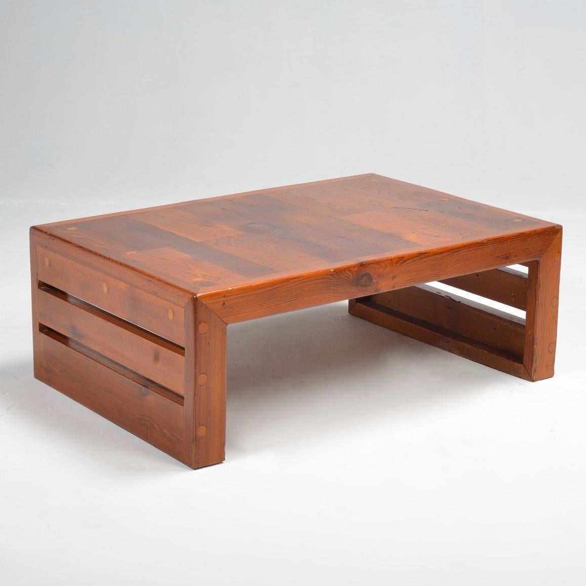 Preciosa mesa de centro de pino macizo con carpintería vista, detalles de espigas circulares y laterales de listones abiertos. Cálida pátina y forma minimalista Brutalista que enfatiza el material y la estructura.