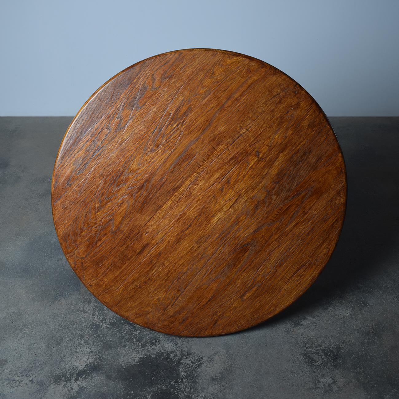 French Brutalist oak coffee table from the 1960s, exemplifying the era's emphasis on raw materials and strong, sculptural forms. Crafted from solid oak, the table features a thick, circular top with a subtly beveled edge, highlighting the rich grain