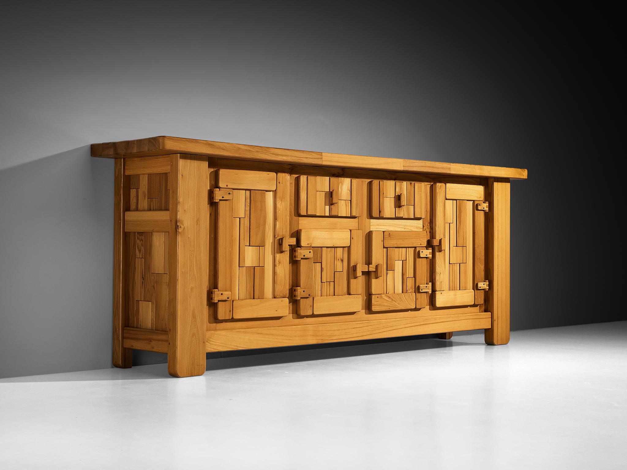 Sideboard, Ulme massiv, Frankreich, 1970er Jahre

Dieses Sideboard ist ein Beispiel für außergewöhnliche Holzverarbeitung, die durch die grafisch gestalteten Türen hervorgehoben wird, die einen dynamischen und taktilen Rhythmus auf der Vorderseite
