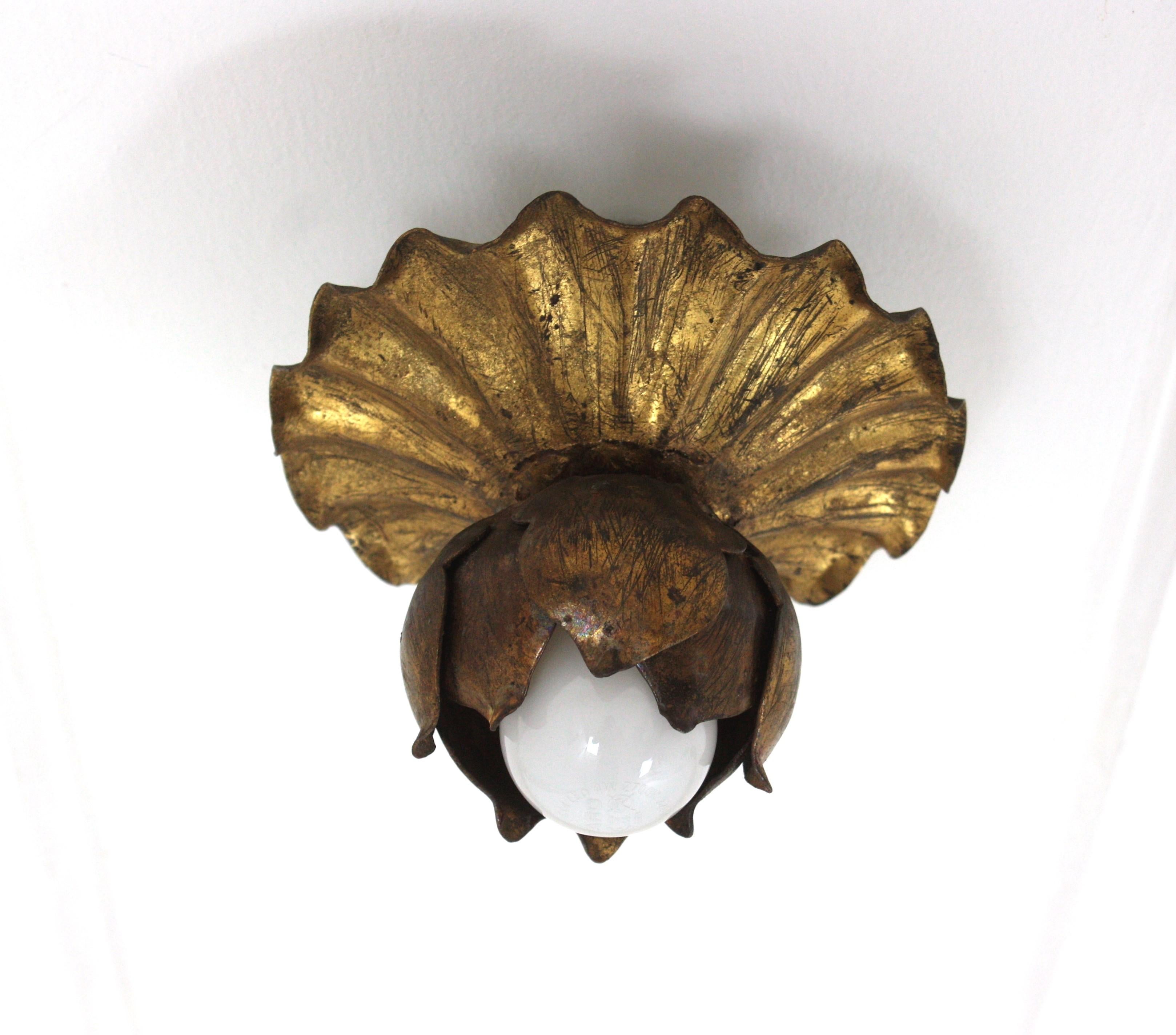 Single Light Flower Bud Ceiling Light Fixture / Wall Light, Gilt Iron, Gold Leaf
France, 1950s
A beautiful Hollywood Regency gilt wrought iron floral flush mount or wall sconce. This lovely light fixture features an scalloped round backplate with