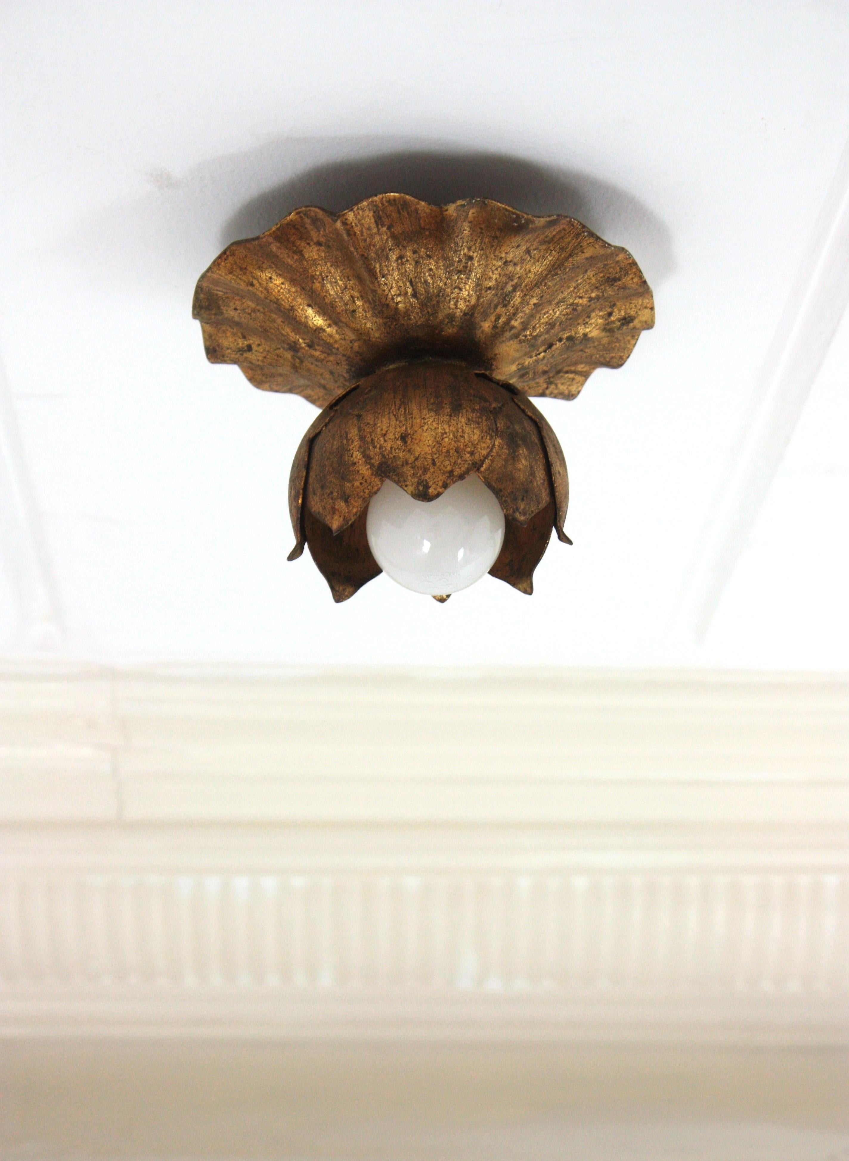 Single Light Flower Bud Ceiling Light Fixture / Wall Light, Gilt Iron, Gold Leaf
France, 1950s
A beautiful Hollywood Regency gilt wrought iron floral flush mount or wall sconce. This lovely light fixture features an scalloped round backplate with
