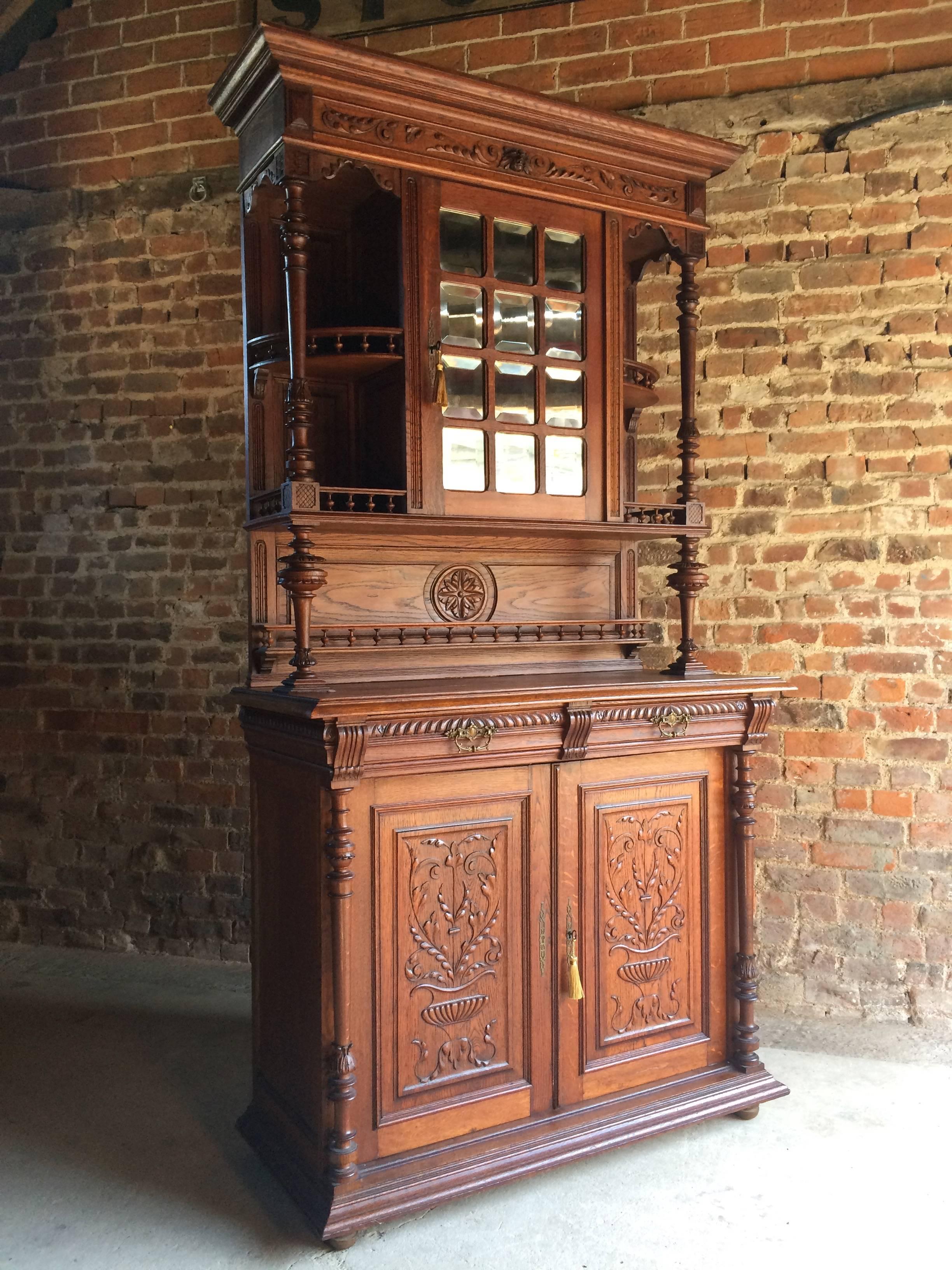 A magnificent heavily carved antique 19th century French Gothic revival solid oak buffet cabinet, circa 1875, the upper section with over hanging cornice above a central cupboard with mirror panelled door enclosing a single shelf, two pilaster