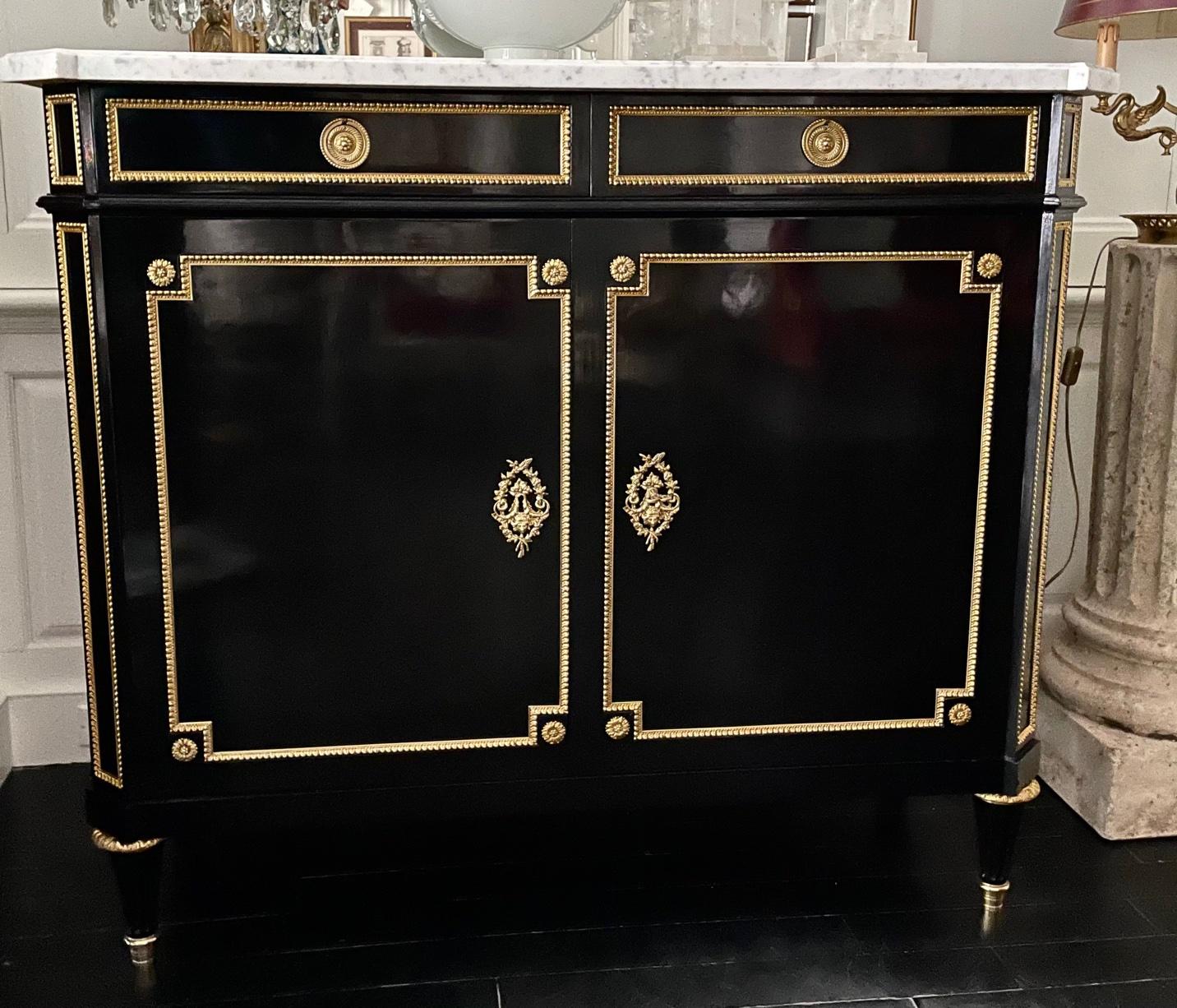 French buffet cabinet, Louis XVI style, ebonized with marble top, early 20th century. In the spirit of Hollywood Regency and Maison Jansen.
The drawers are lined in red velvet. The double doors open to reveal neat oak shelves.
Gilt bronze details.