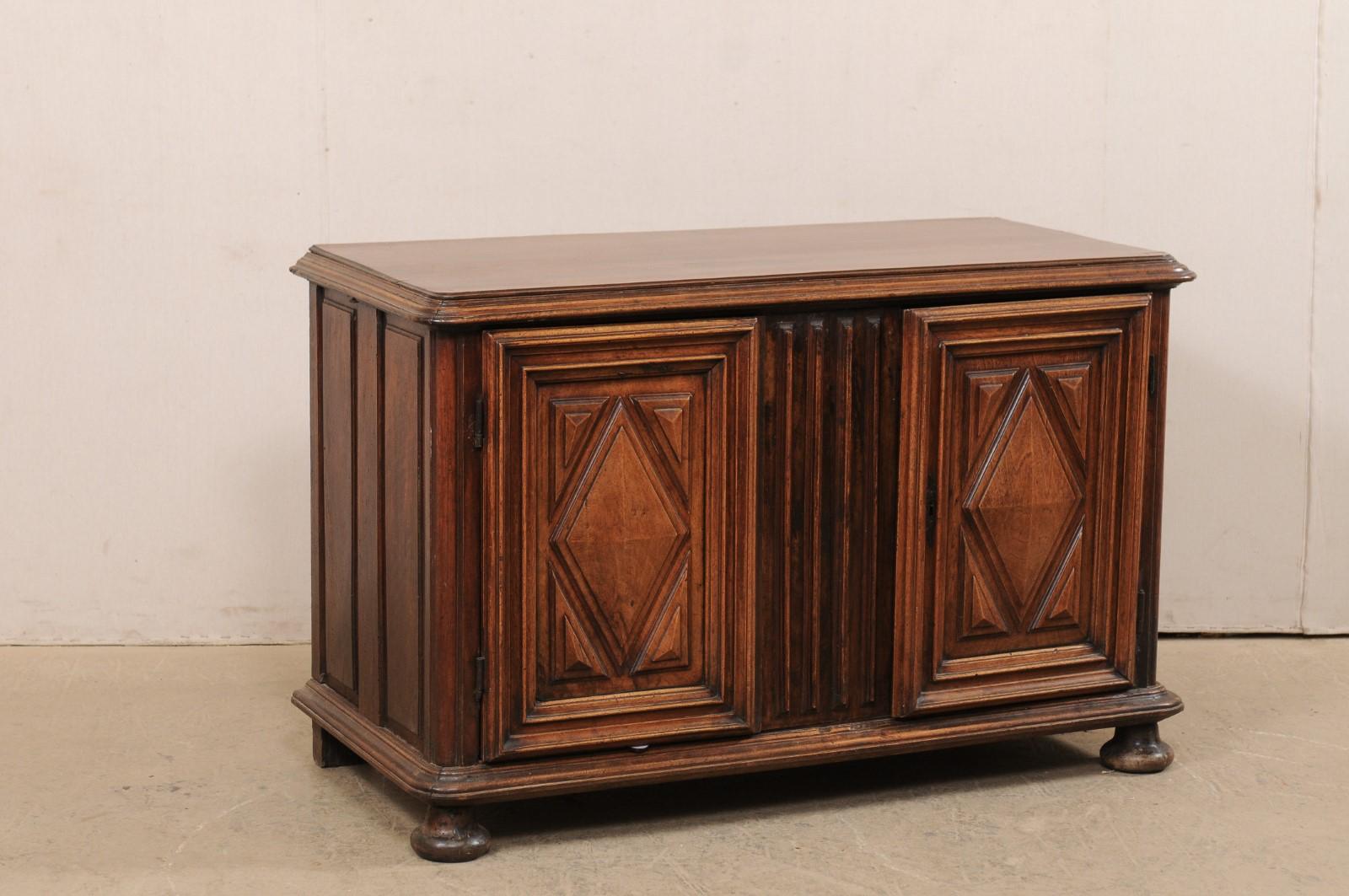 A French decoratively carved wood buffet cabinet from the early 19th century. This antique cabinet from France features a rectangular-shaped top with molded edging and curved front corners, and artfully adorn with thick reed carvings at front