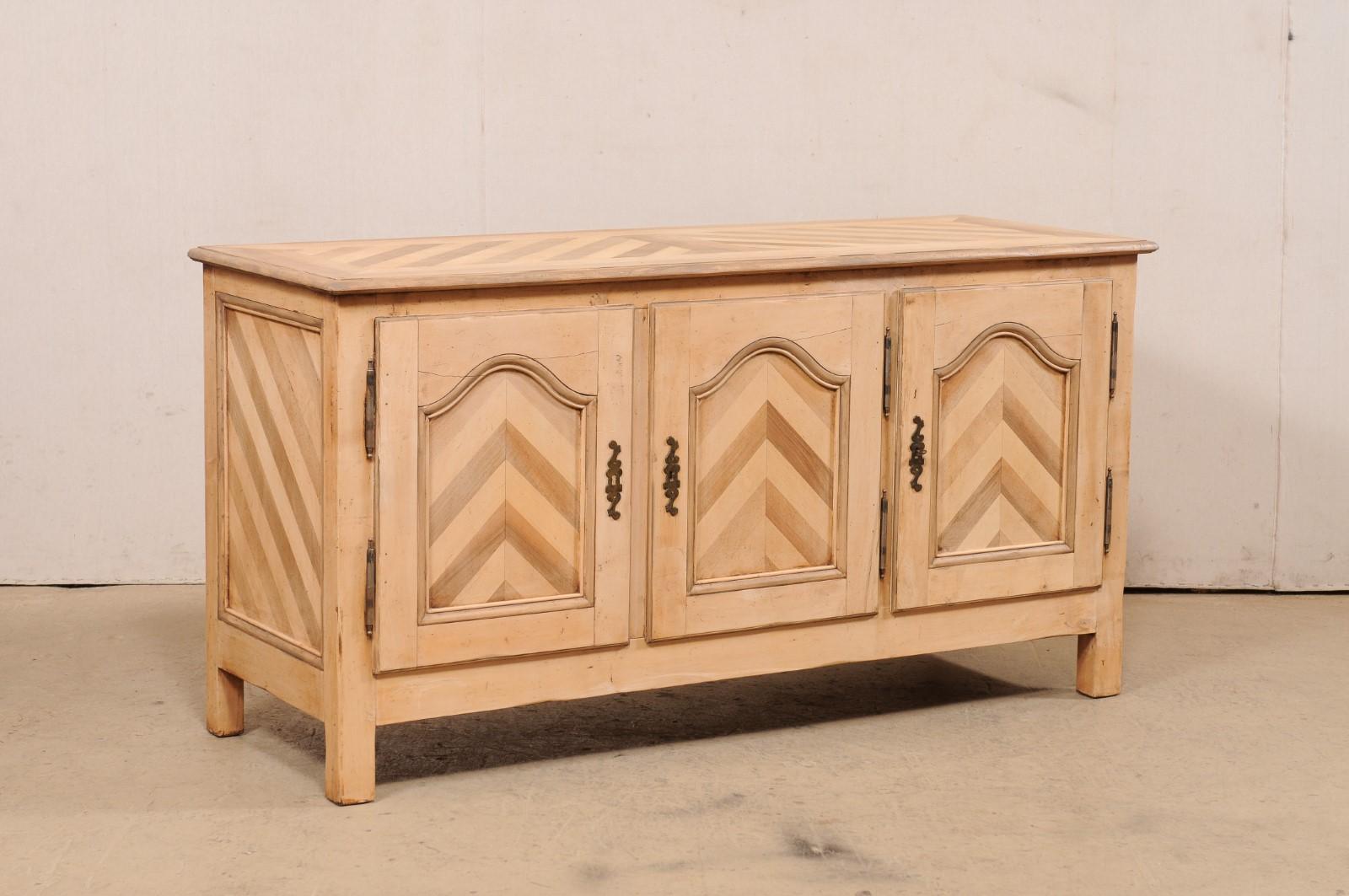 A French wooden buffet cabinet from the mid 20th century. This vintage French sideboard, approximately 5.75 feet in length, is uniquely embellished with an inlaid wood pattern of angular lines that create a wonderful chevron pattern on the door