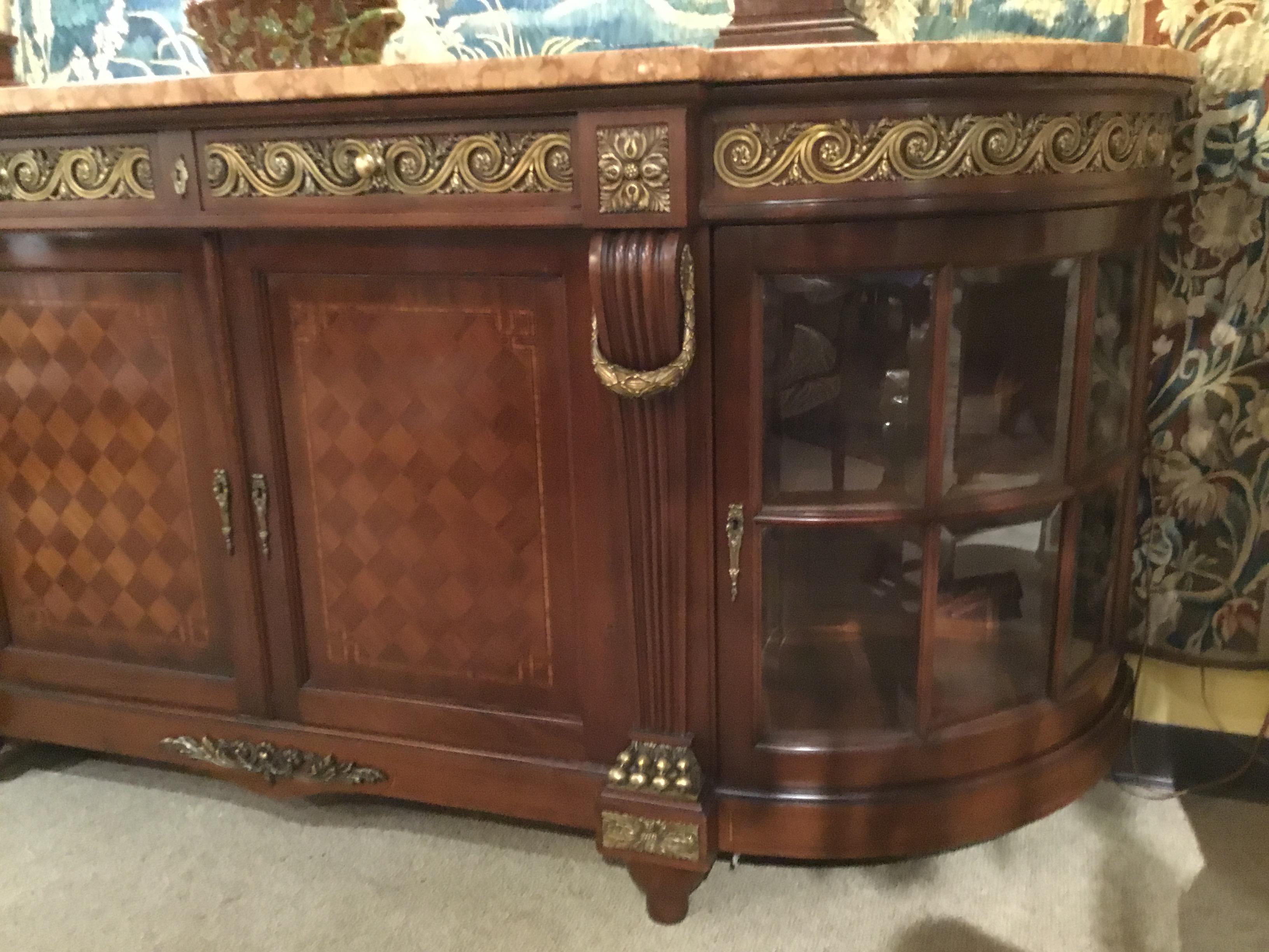 Large and impressive sideboard with a marble top and lovely bronze mounts. Curved sides
add a graceful presentation. The side doors open to one shelf. Beveled glass panels on
each side make this a great display. Two drawers open at the center top