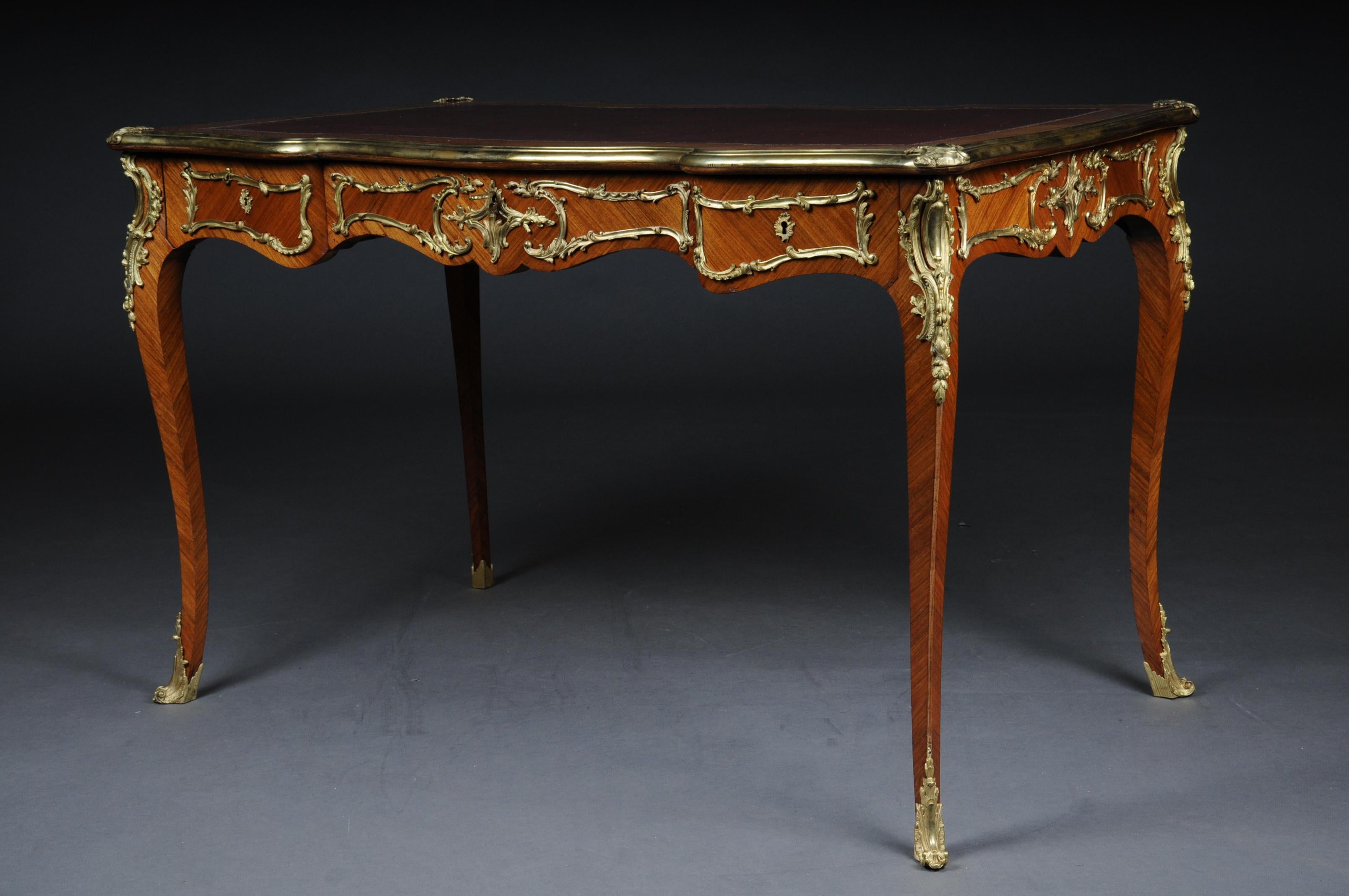 French Bureau plat / desk in Louis XV, Paris, circa 1880.

Solid beech wood veneer. Extremely fine, floral bronze fittings.
Cambered and pronounced / arched wooden body. Four-sided curved frame base.
3 drawers and a wide knee compartment on