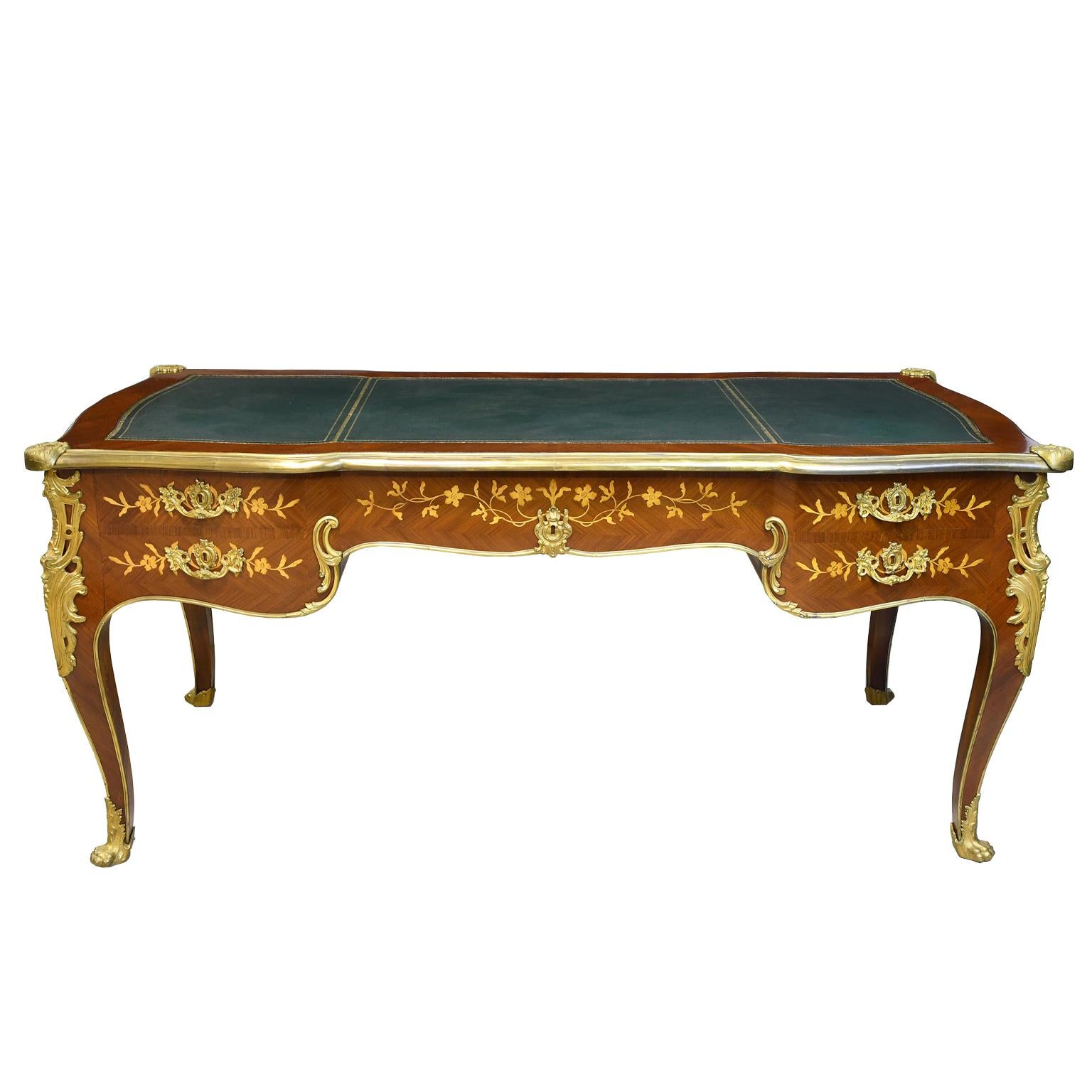 A very beautiful and well-crafted French bureau plat desk in fine mahogany with parquetry & satinwood marquetry inlays of flowers & foliage that have been hand-colored. The finely articulated ormolu mounts, sabots, and hardware were originally