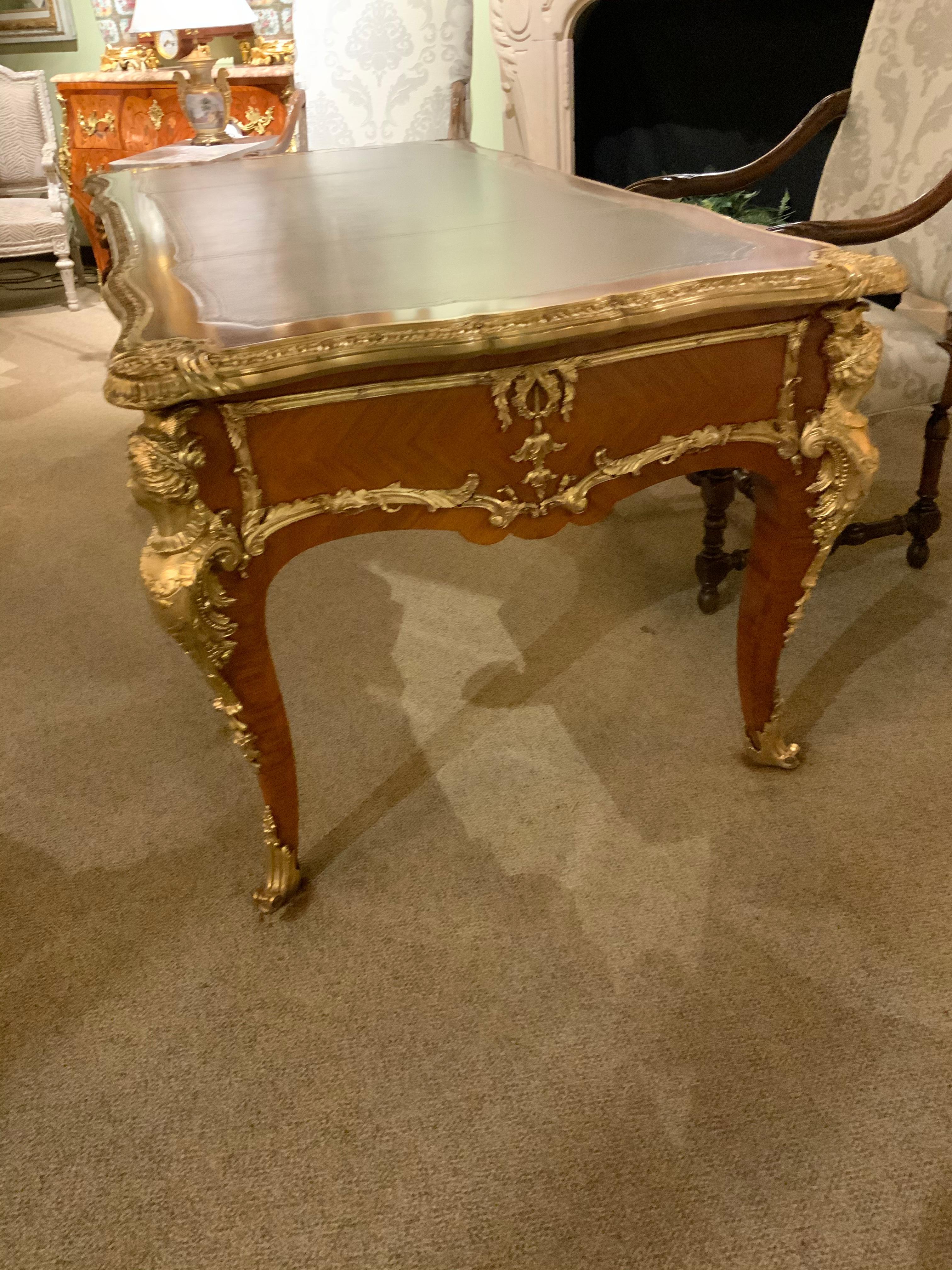French bureau plat with bronze ormolu mounts in the Louis XV style. The
Wood is mahogany, The figural mounts on the corners are gilt bronze,
Three drawers, reverse with faux drawer fronts, cabriole legs, with
Figural mounts, ending in sabots.
 